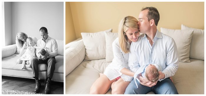new parents sitting on a cream couch holding a newborn baby