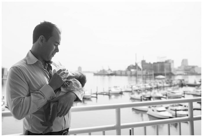 father feeding a bottle to a newborn baby on a Baltimore balcony