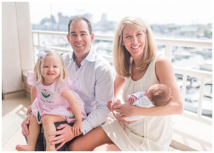 family of four smiling on a balcony overlooking Baltimore maryland