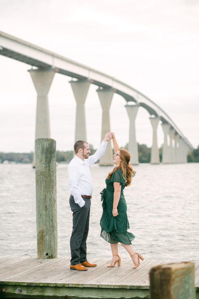 A portrait of a man and woman dancing on a pier next to the Thomas Johnson Bridge in Solomons, Maryland