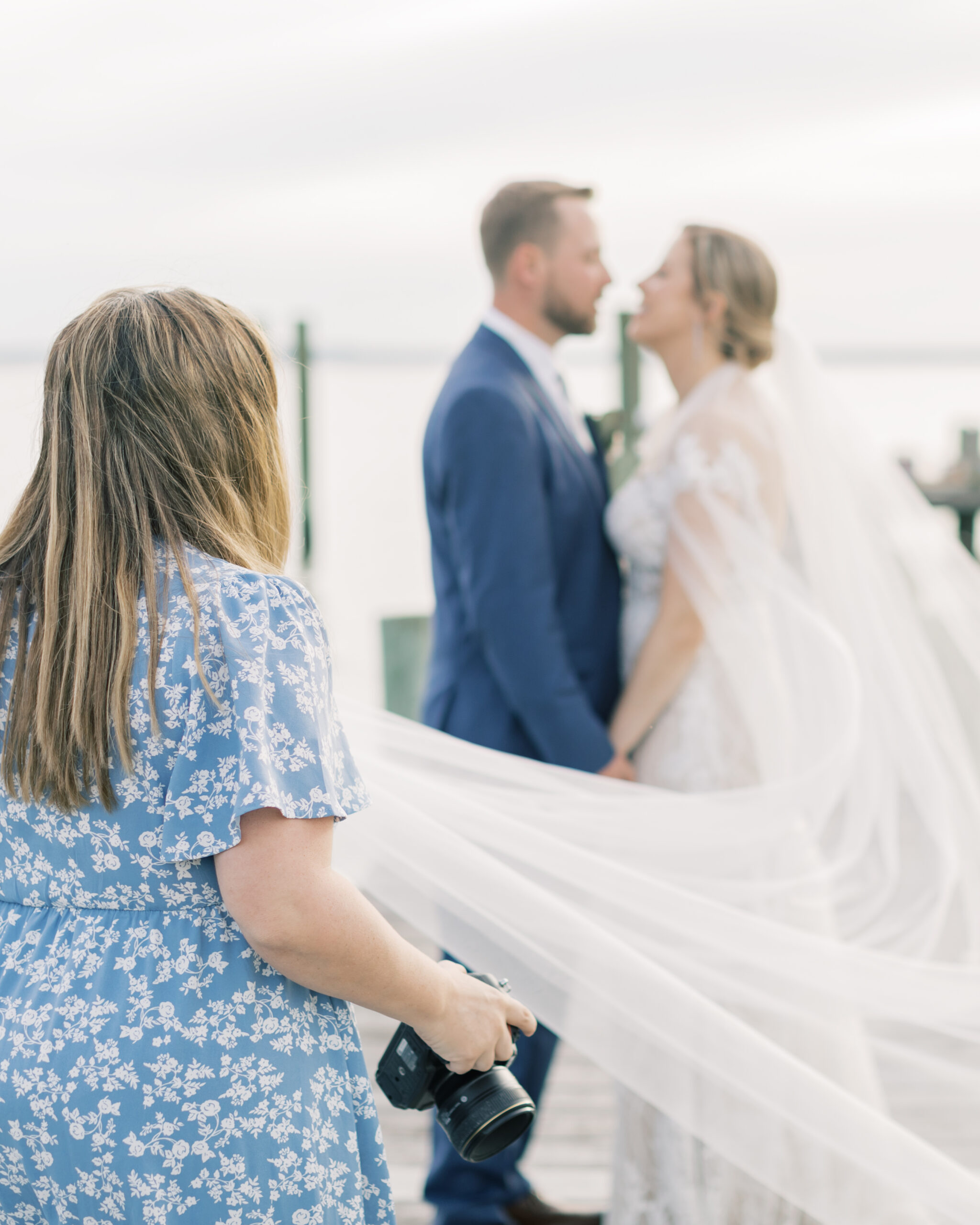 Amanda Wose stands behind a man and woman on their wedding day