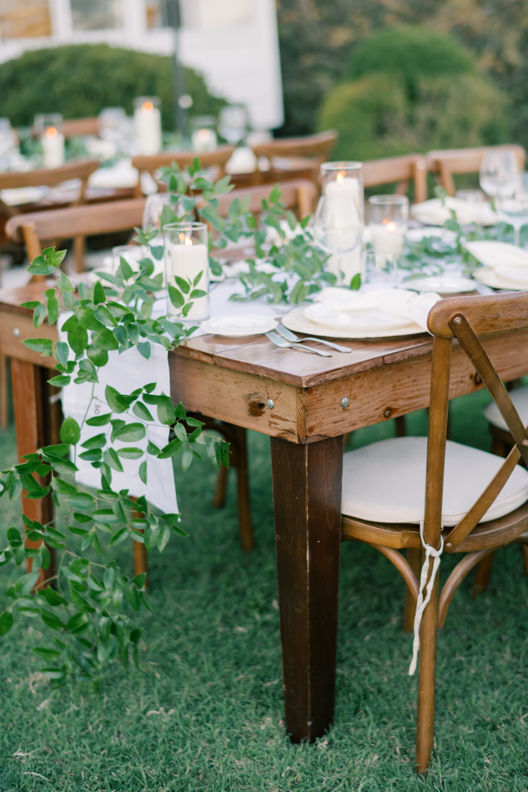 wedding reception with greenery on white table runner with white candles