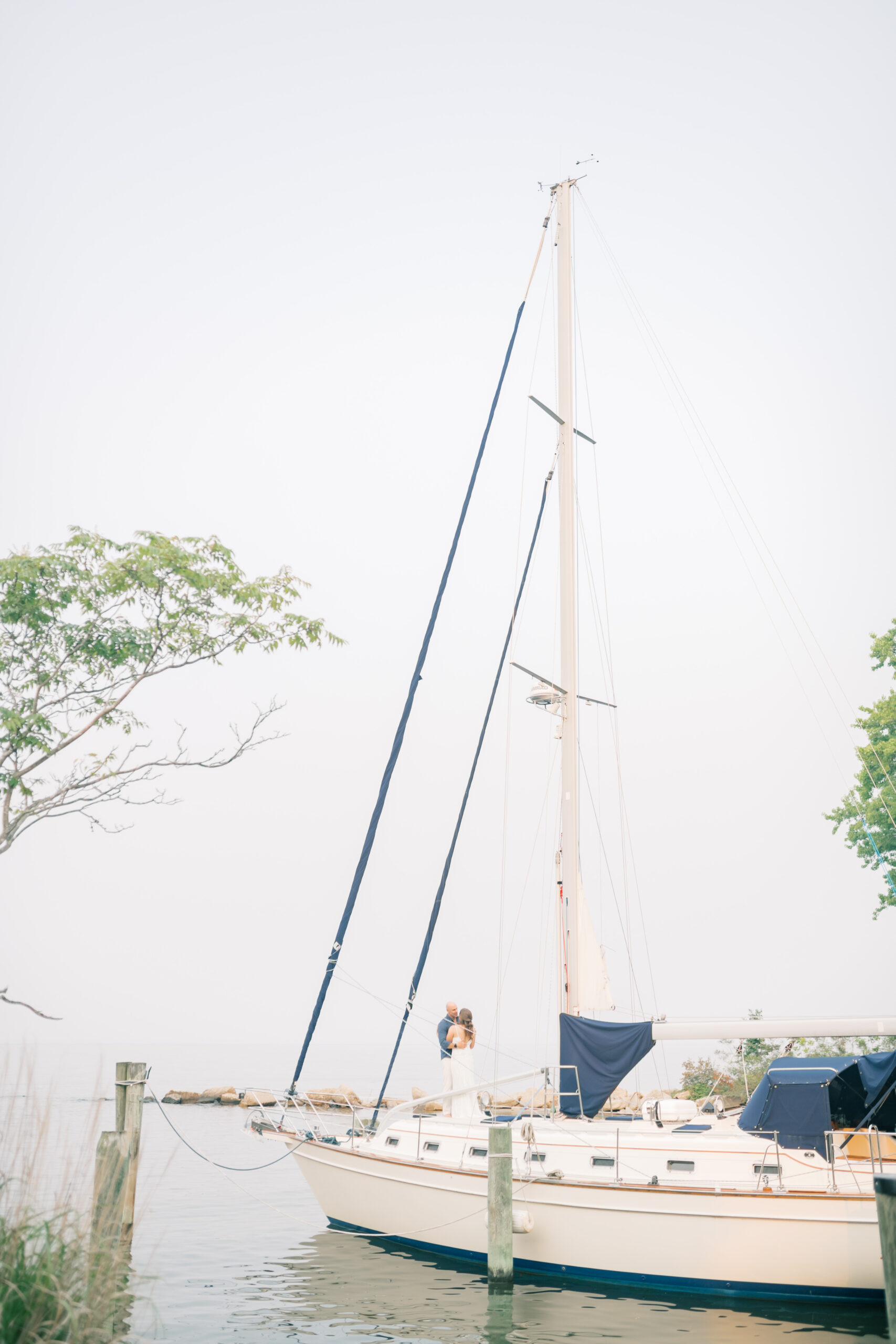 bride and groom hug on sailboat on Maryland River during elopement