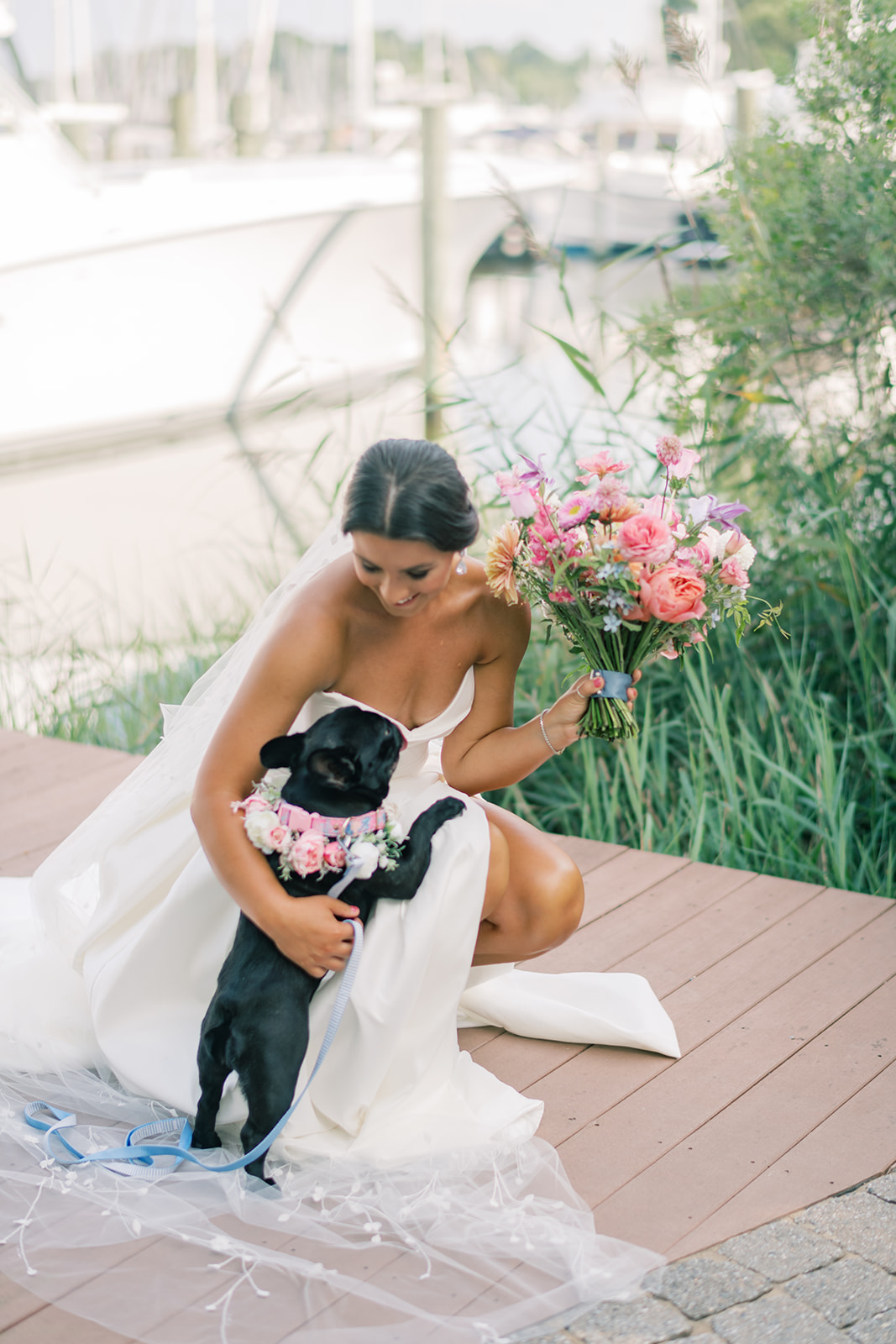 bride kneels down while dog jumps up on her at Herrington on the Bay