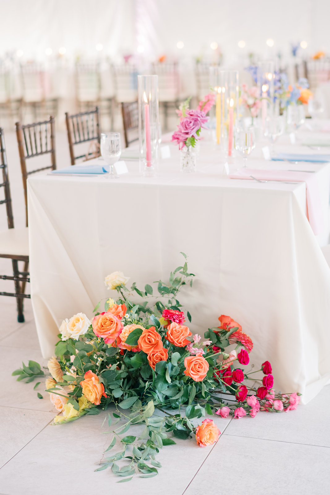 wedding reception with orange and red roses near end of table