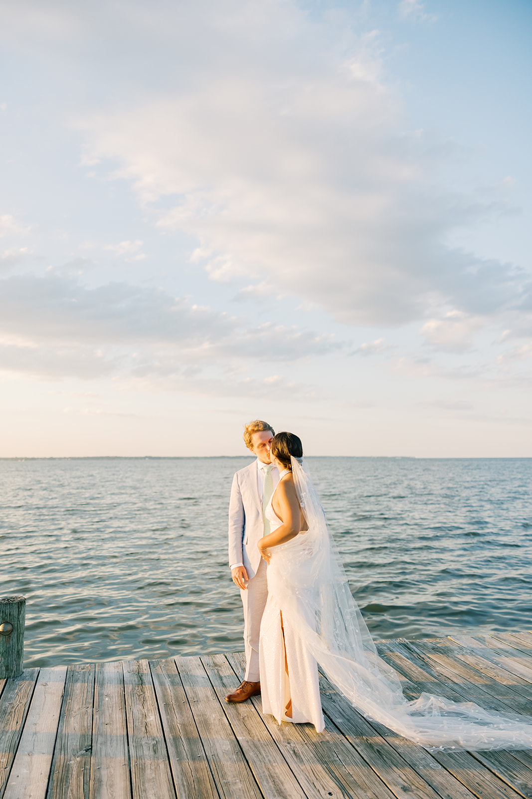 bride and groom kiss walking on dock near Chesapeake Bay