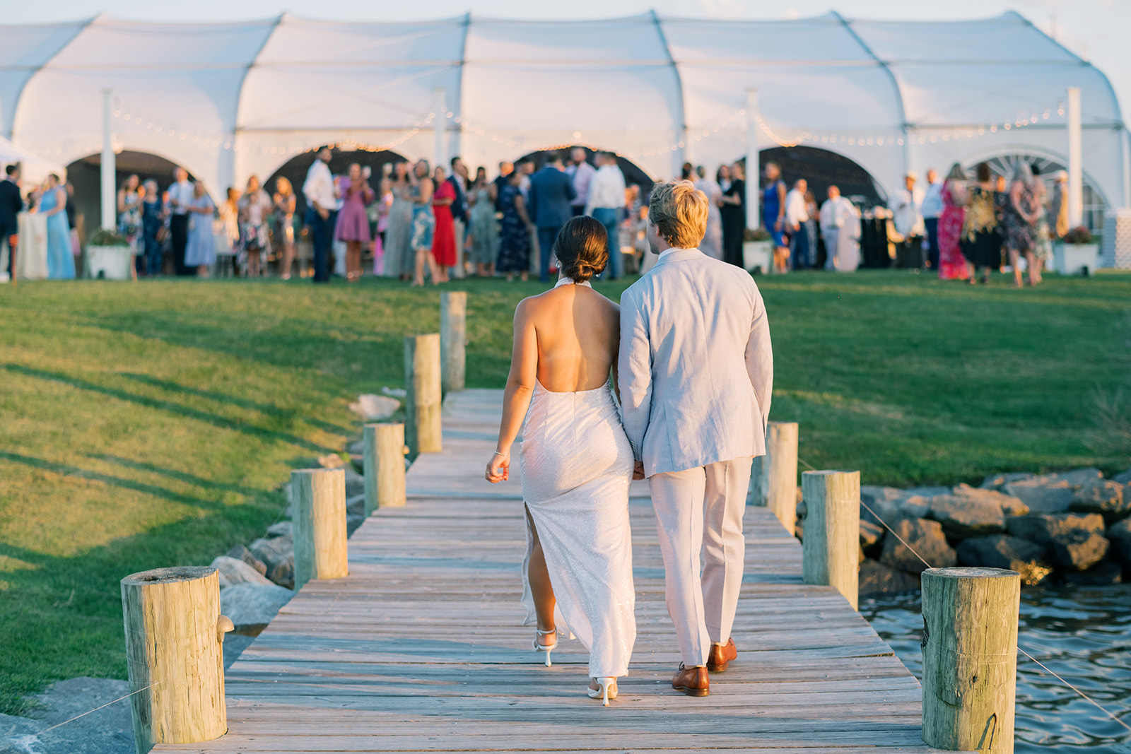 newlyweds hold hands walking up docks for reception at Herrington on the Bay