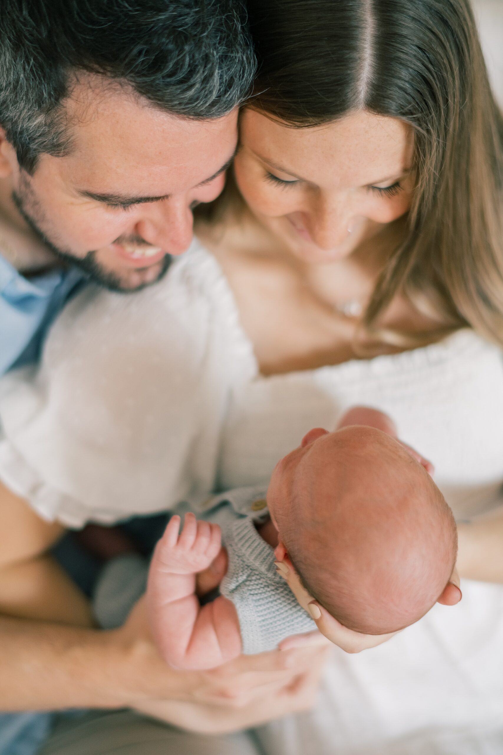 parents snuggle looking down at baby boy during Annapolis lifestyle newborn portraits