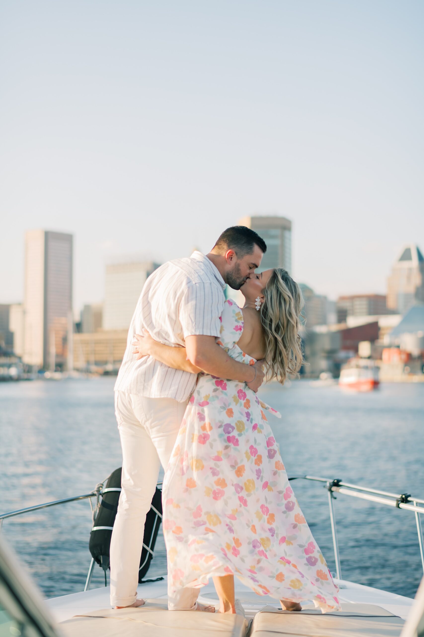 engaged couple kisses on the front of a boat sailing around the Inner Harbor in Baltimore MD