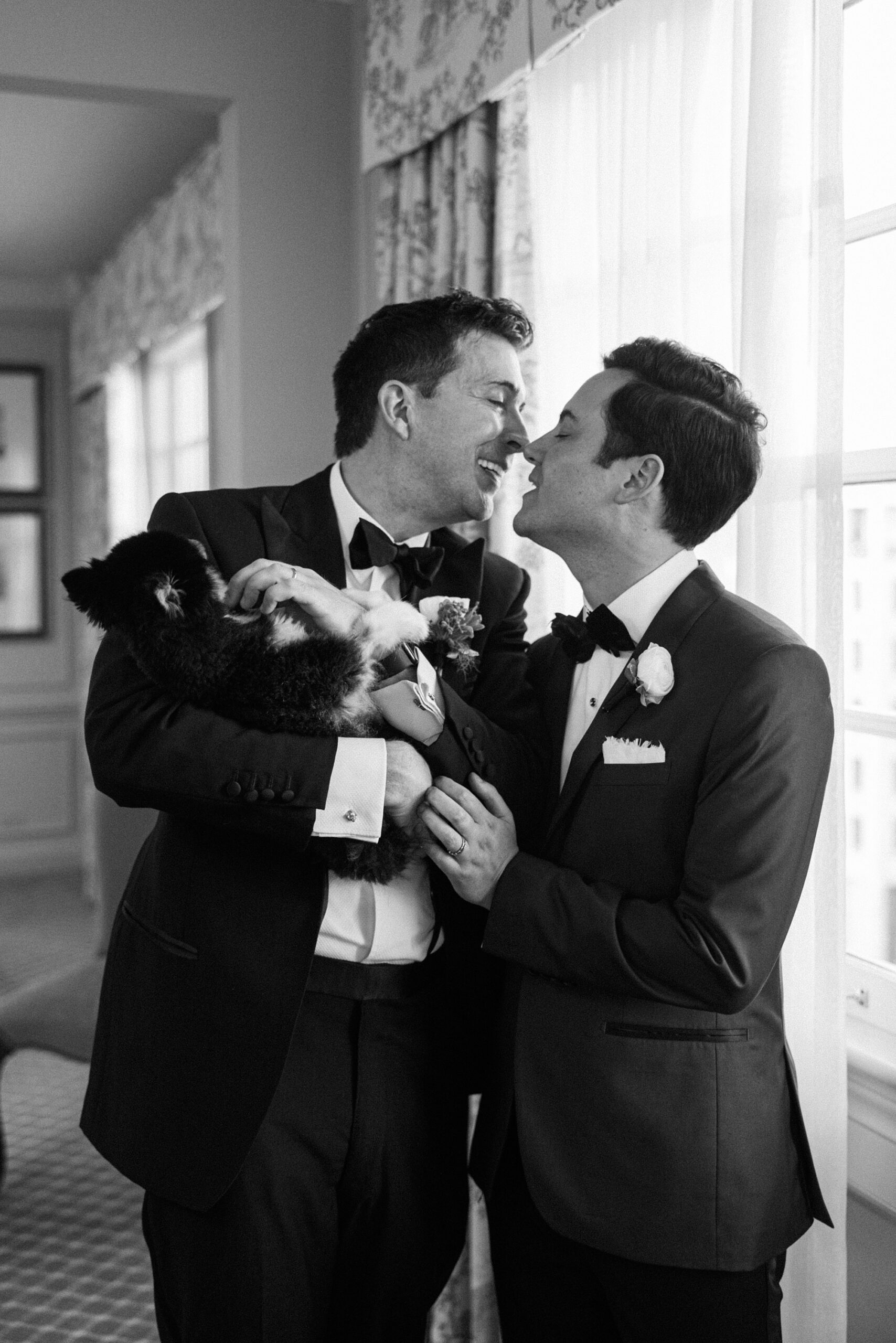 grooms lean to kiss pouring wine during portraits at the Hay Adams Hotel