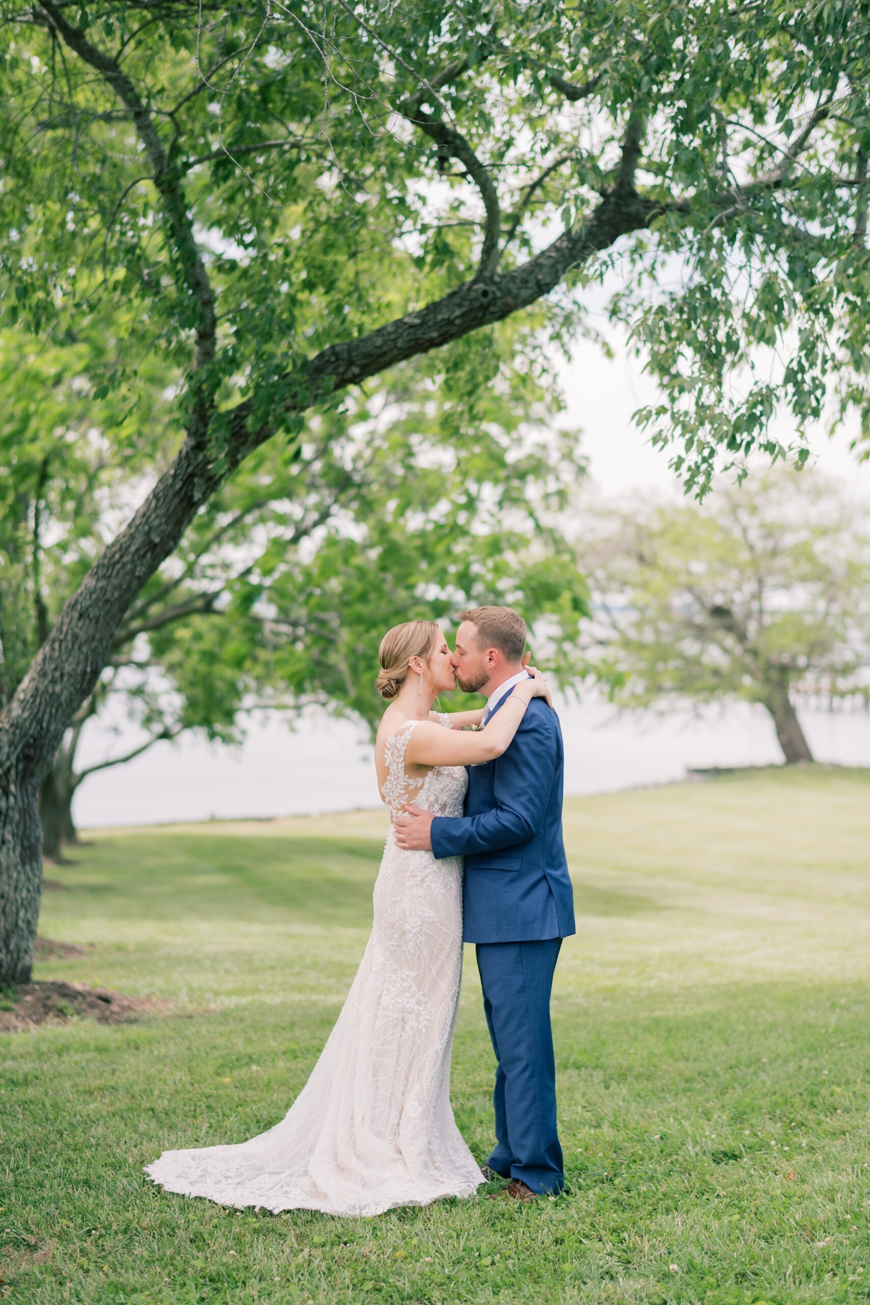 bride and groom hug under tree kissing during MD wedding photos