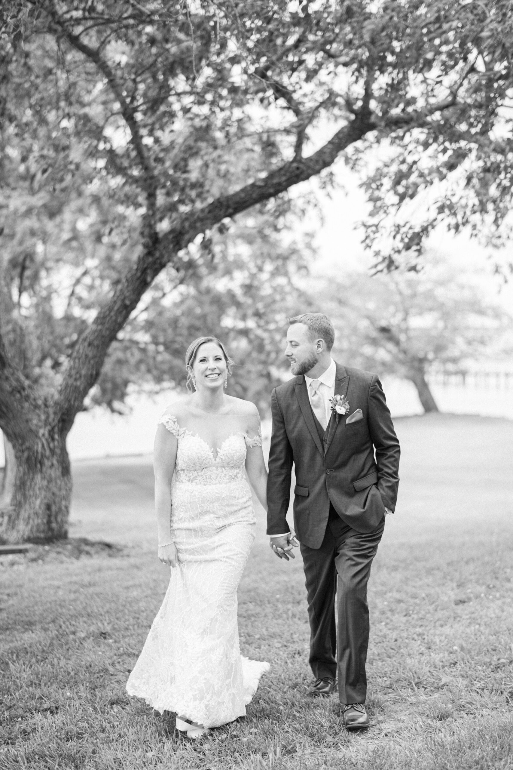 bride and groom hold hands walking away from tree at the Pavilion at Weatherly