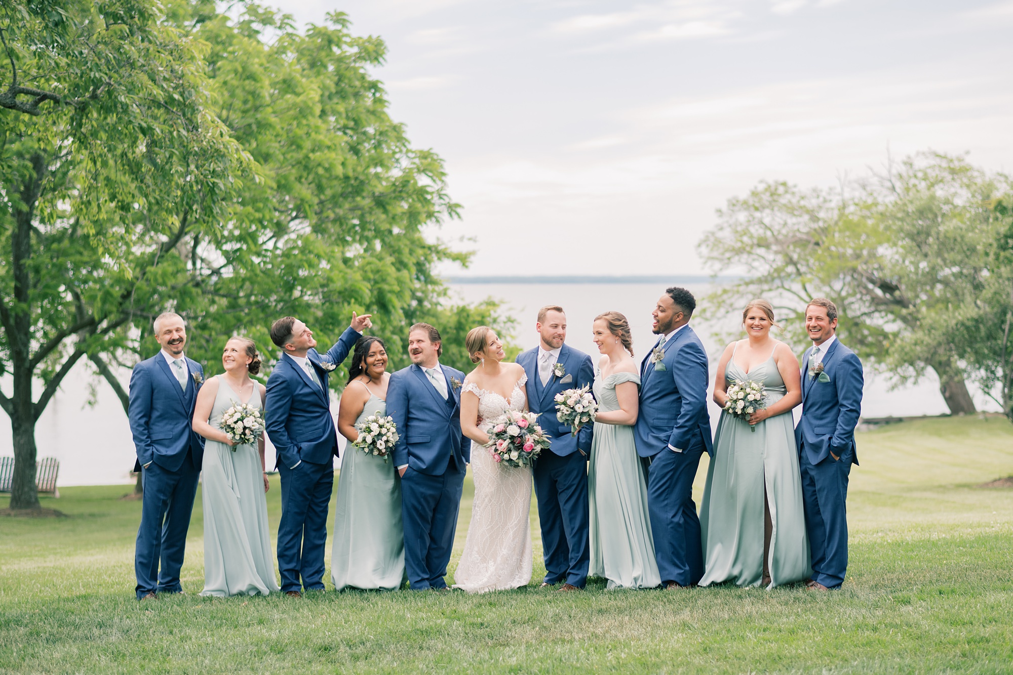 bride and groom pose with wedding party in navy suits and mint green gowns 