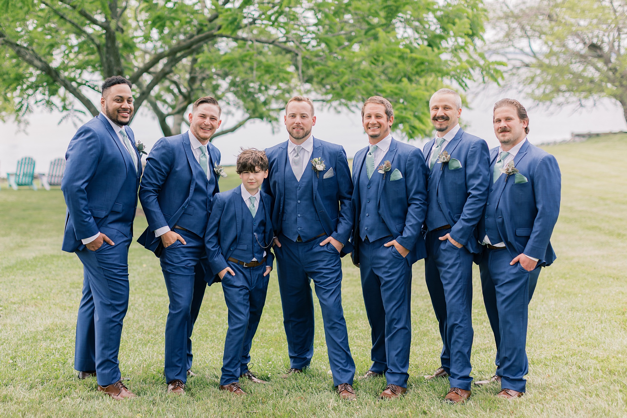groom stands with groomsmen in navy suits on lawn at the Pavilion at Weatherly