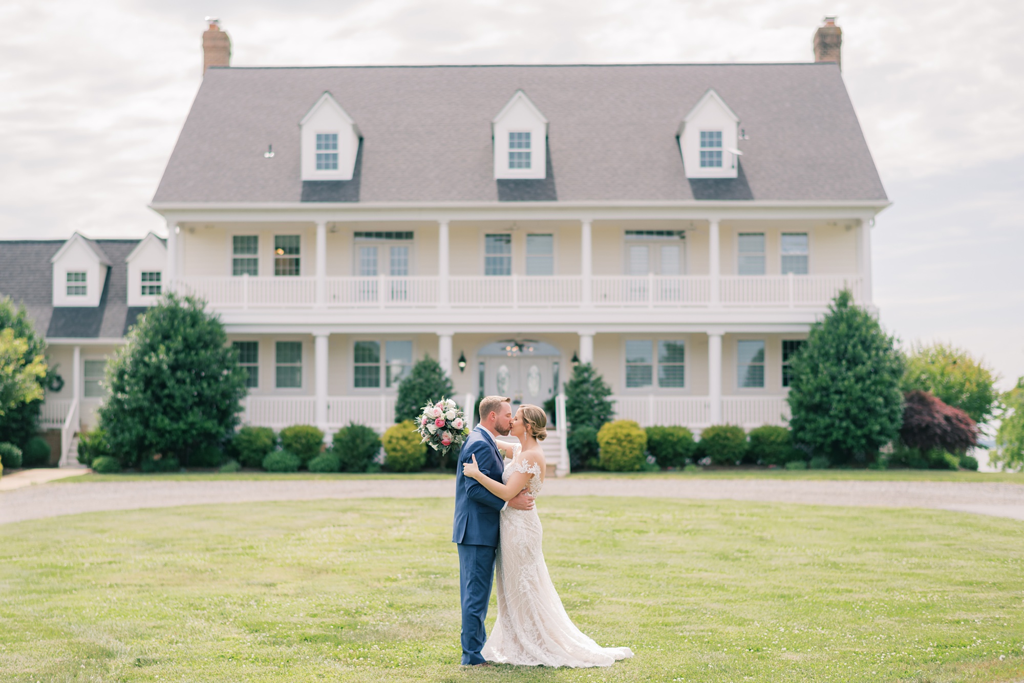 bride and groom kiss in front of the white building at the Pavilion at Weatherly