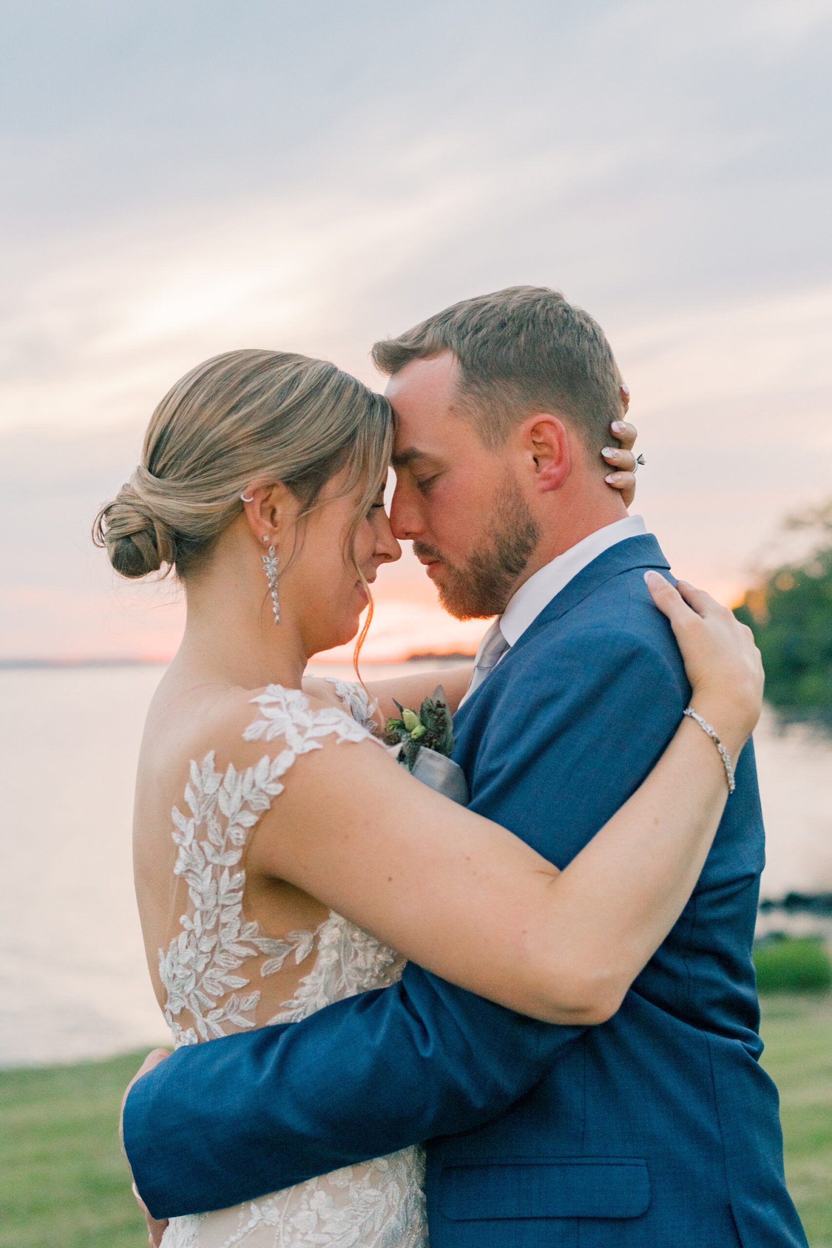 bride and groom hug at sunset along waterfront at the Pavilion at Weatherly