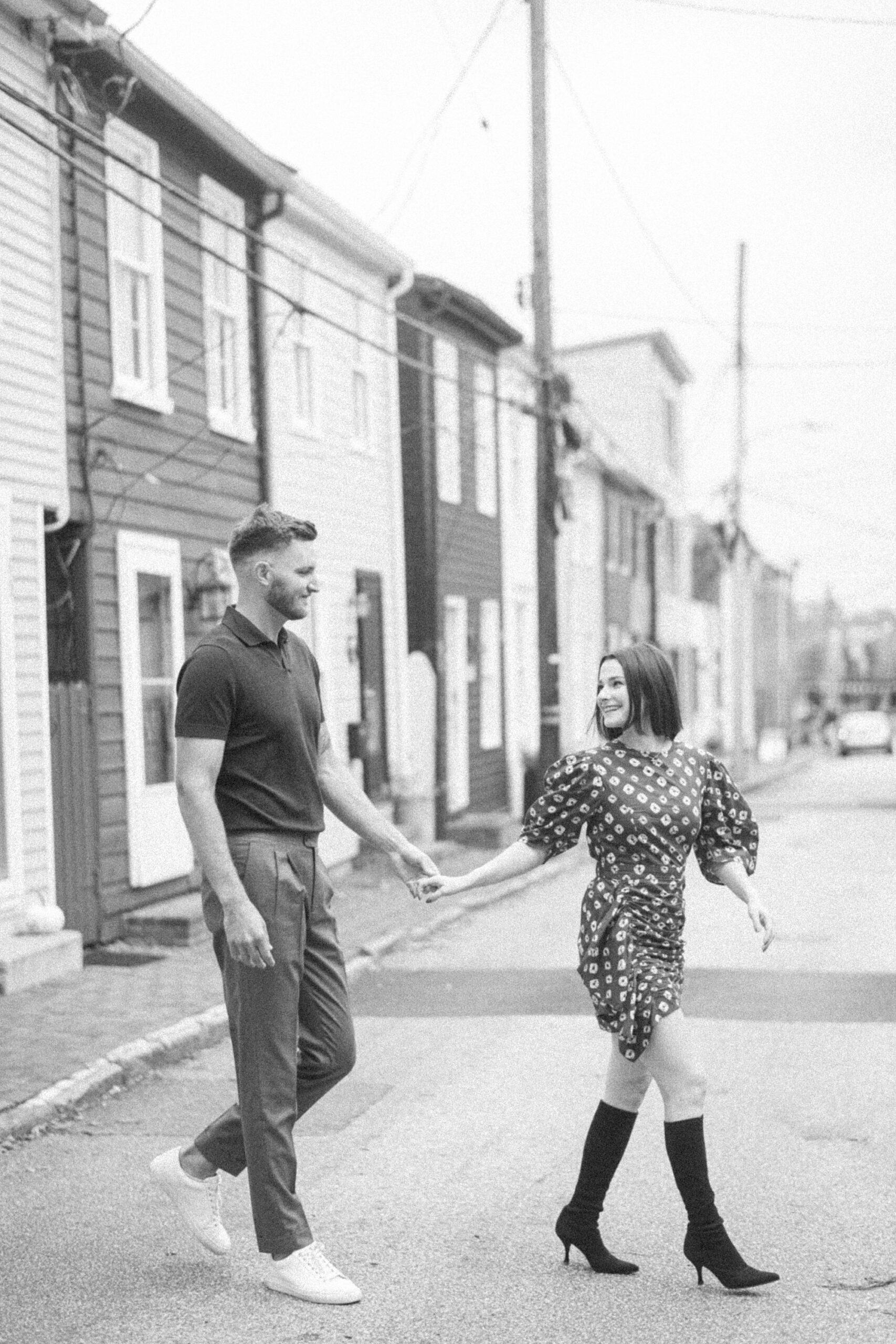 engaged couple holds hands walking across street in Maryland