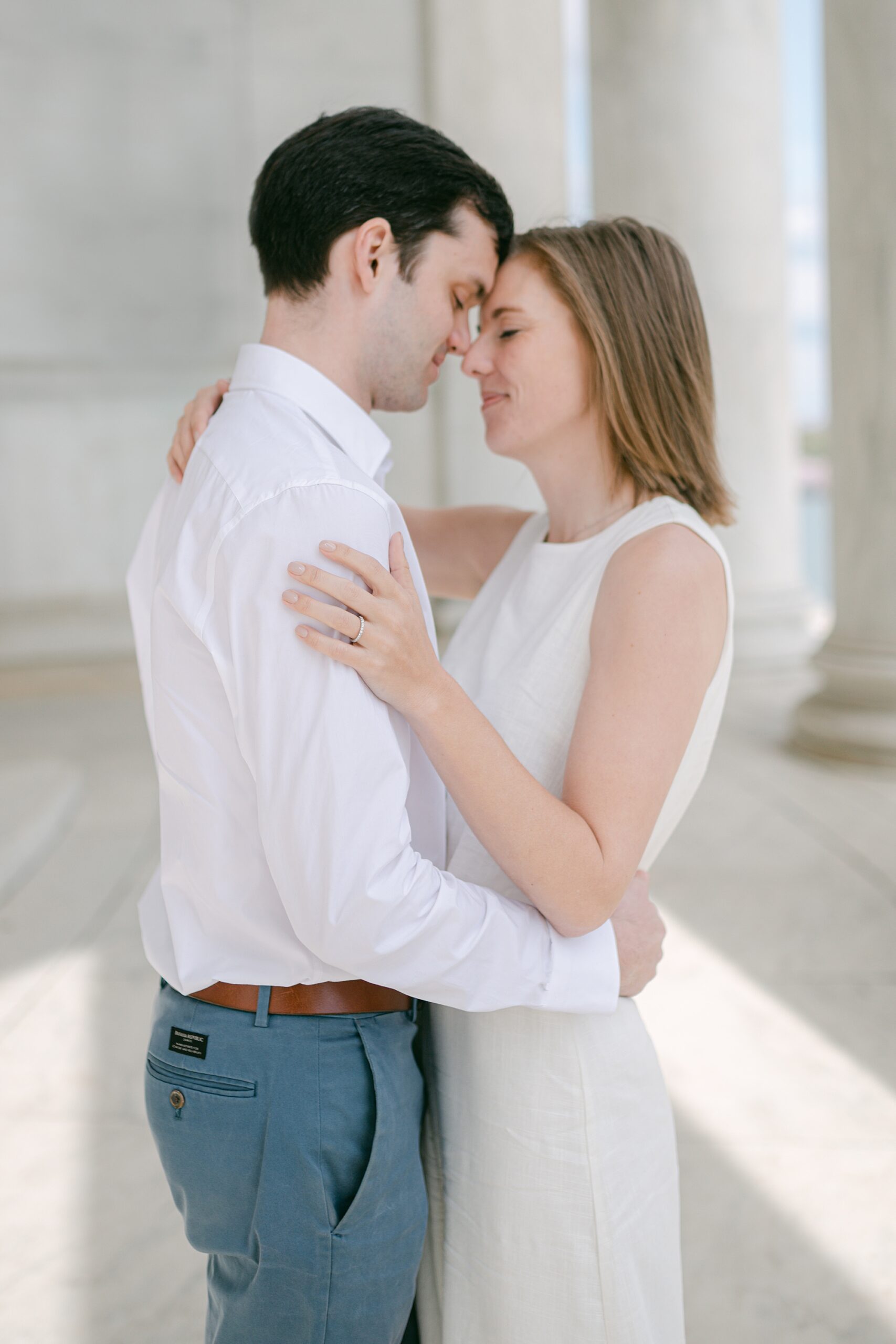 man and woman lean heads together during DC cherry blossom engagement photos