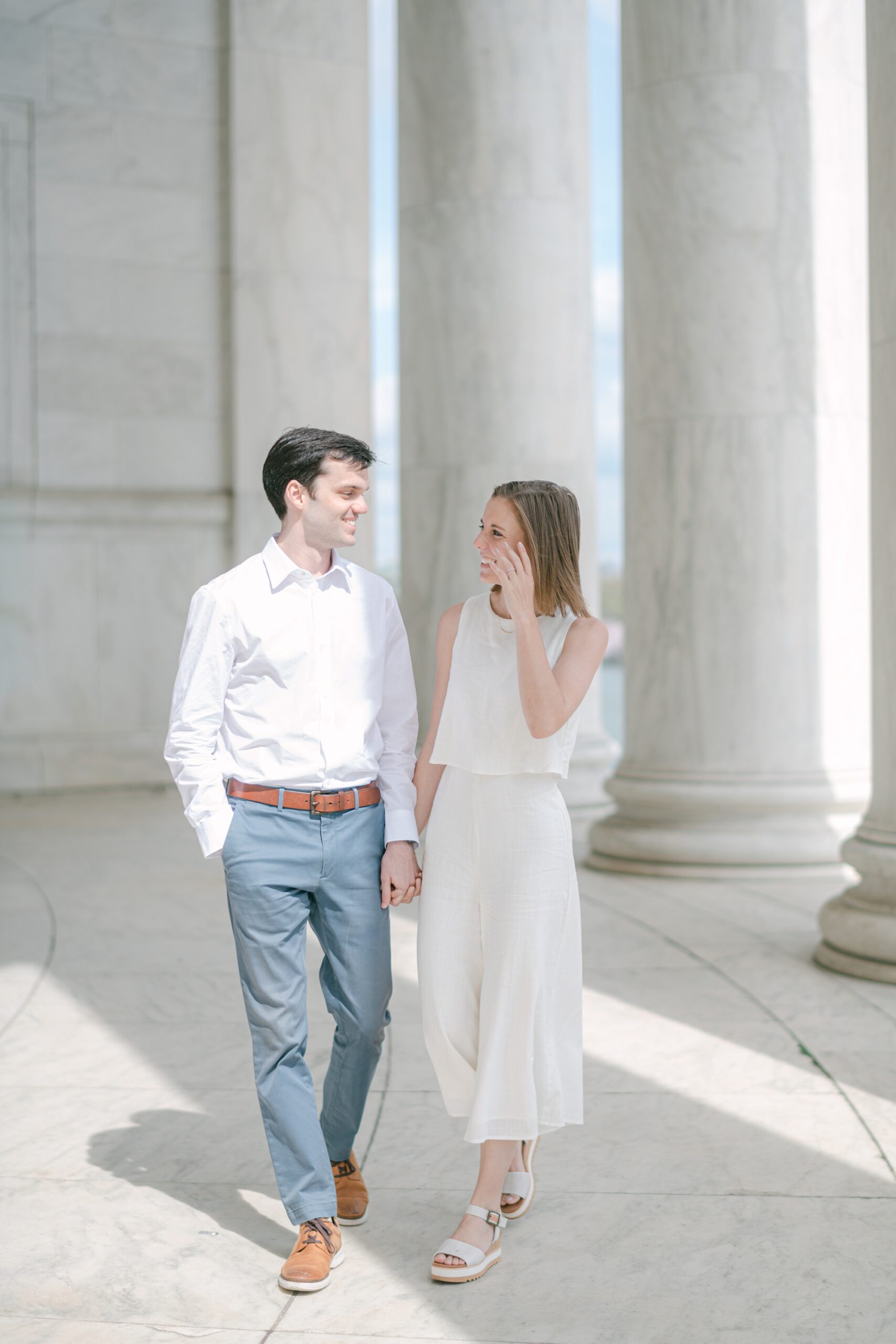 couple holds hands walking through Jefferson Memorial