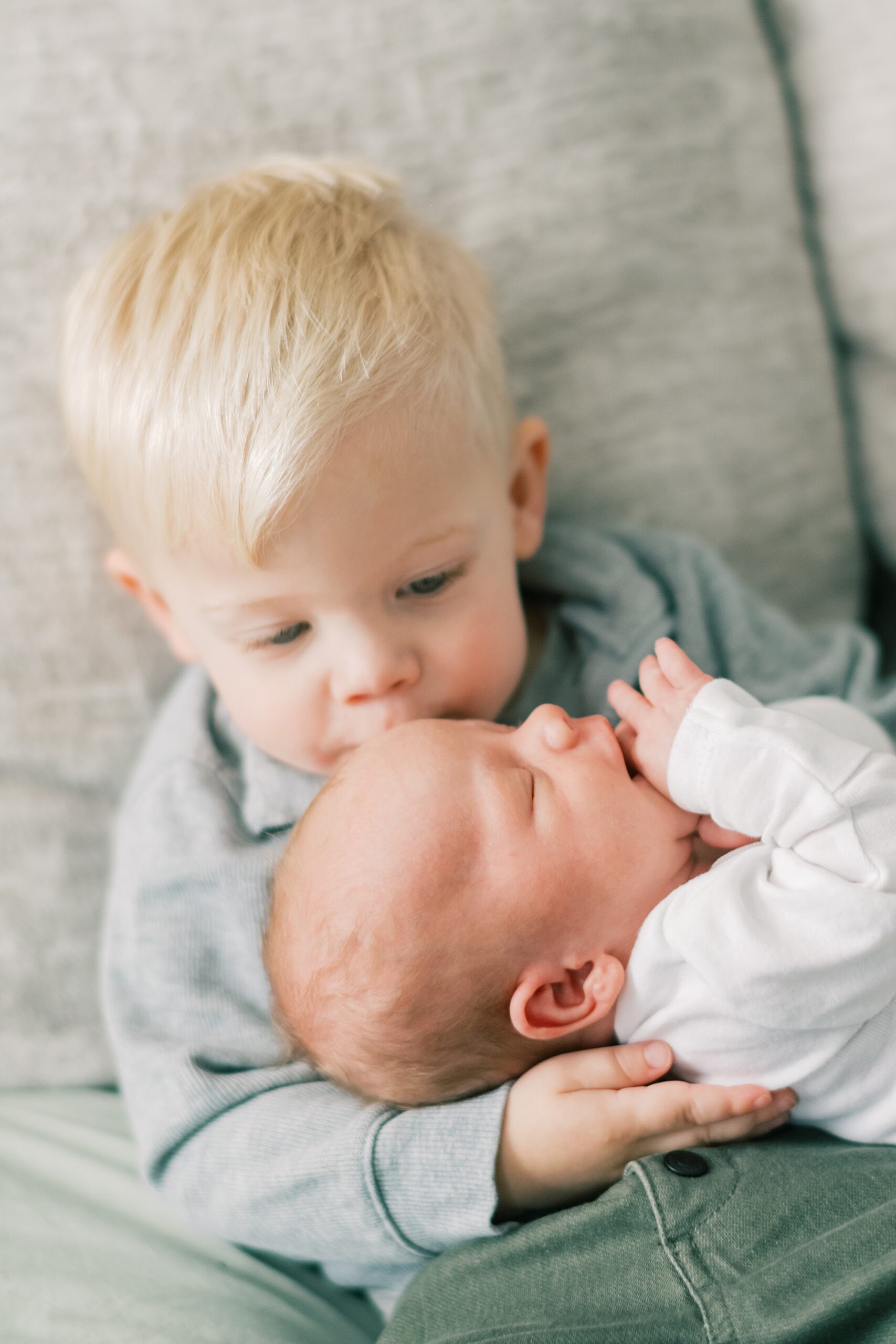 big brother kisses baby during in-home newborn portraits