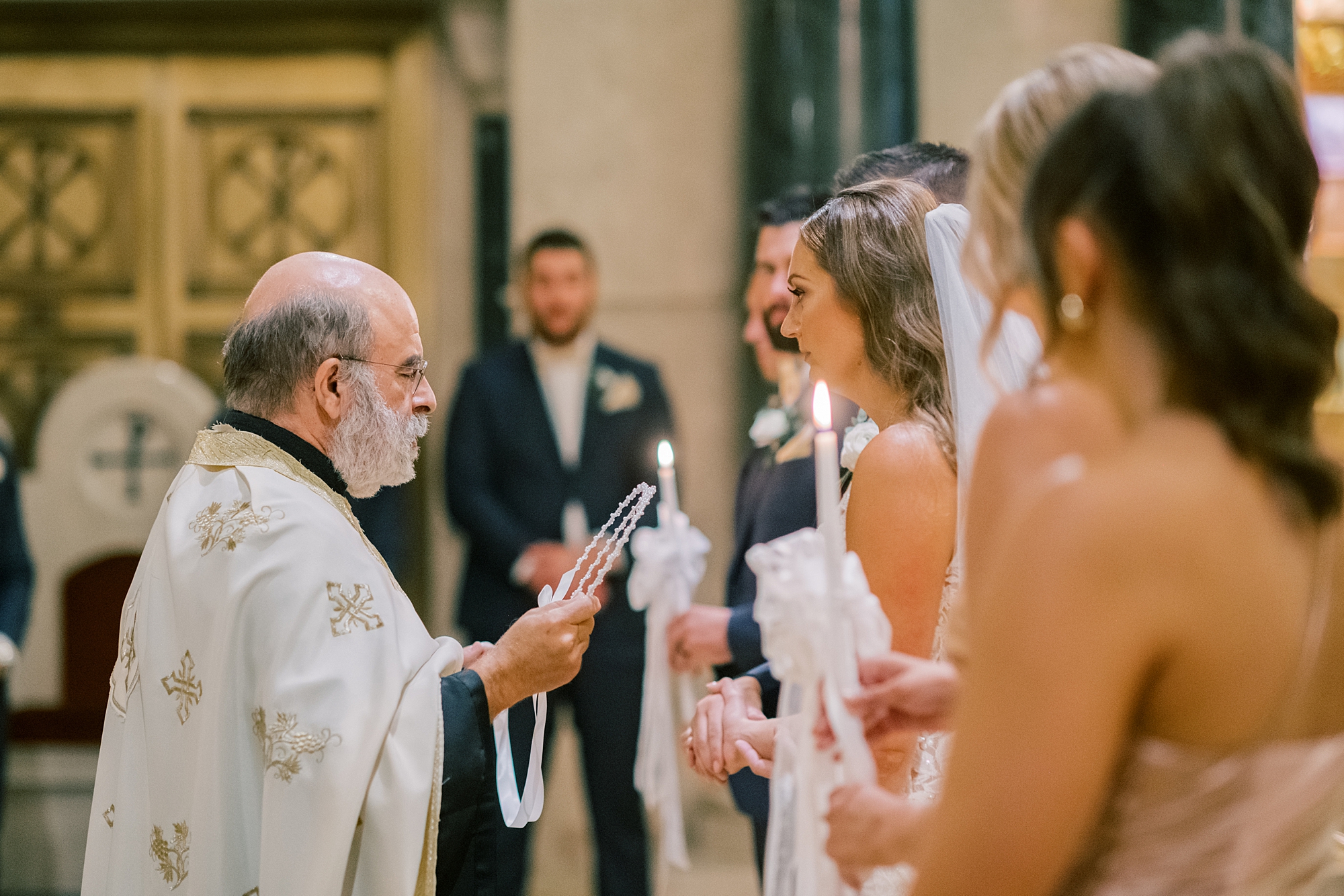 groom lights candles during traditional Greek Orthodox wedding ceremony in Washington DC