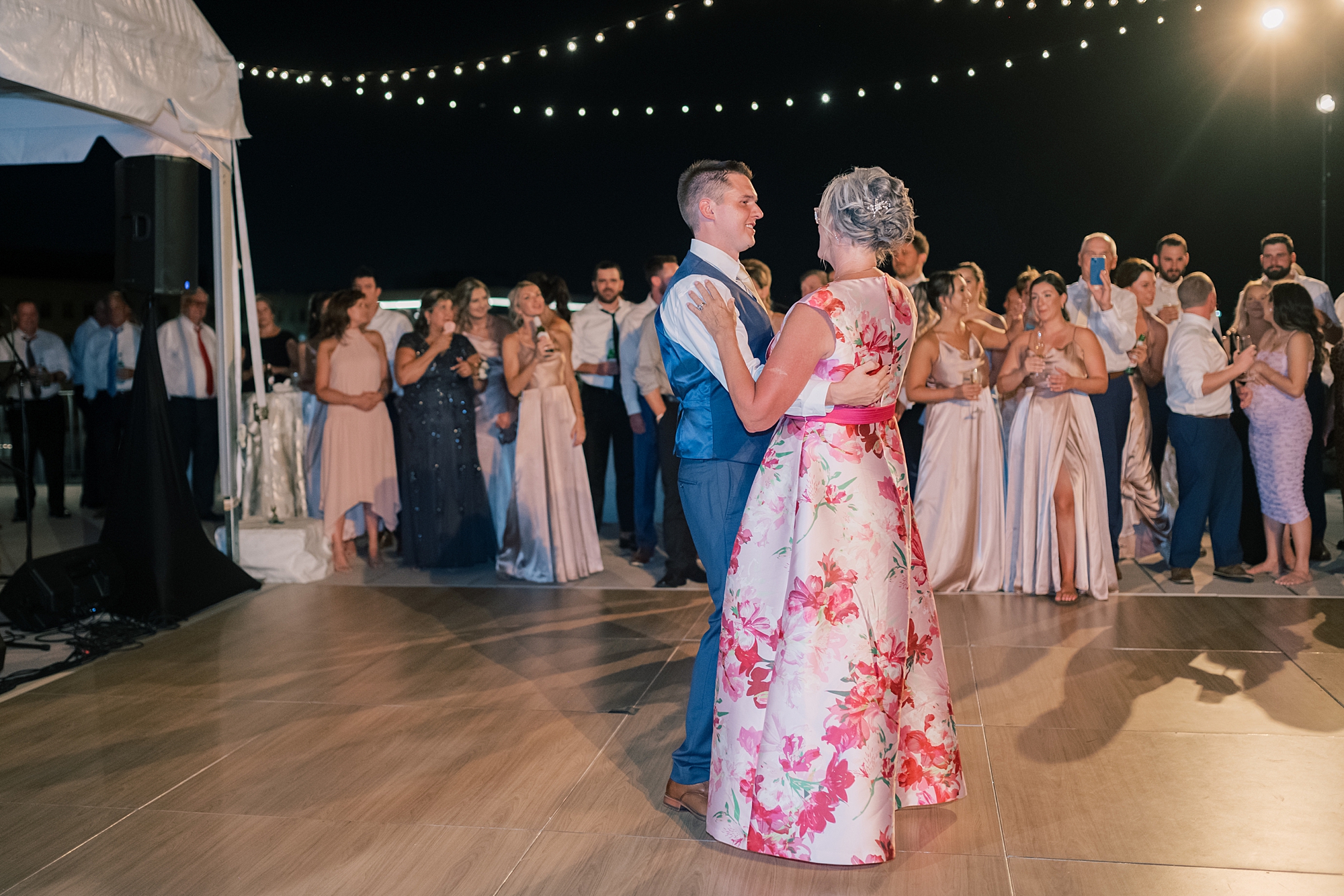 groom dances with mother under bistro lights at Potomac View Terrace wedding