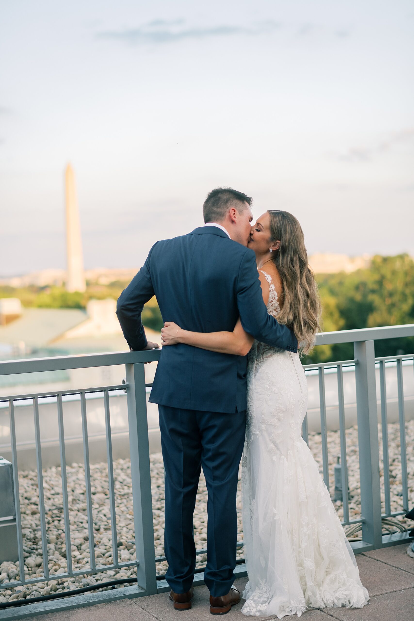 newlyweds kiss on balcony of Potomac View Terrace overlooking Washington DC