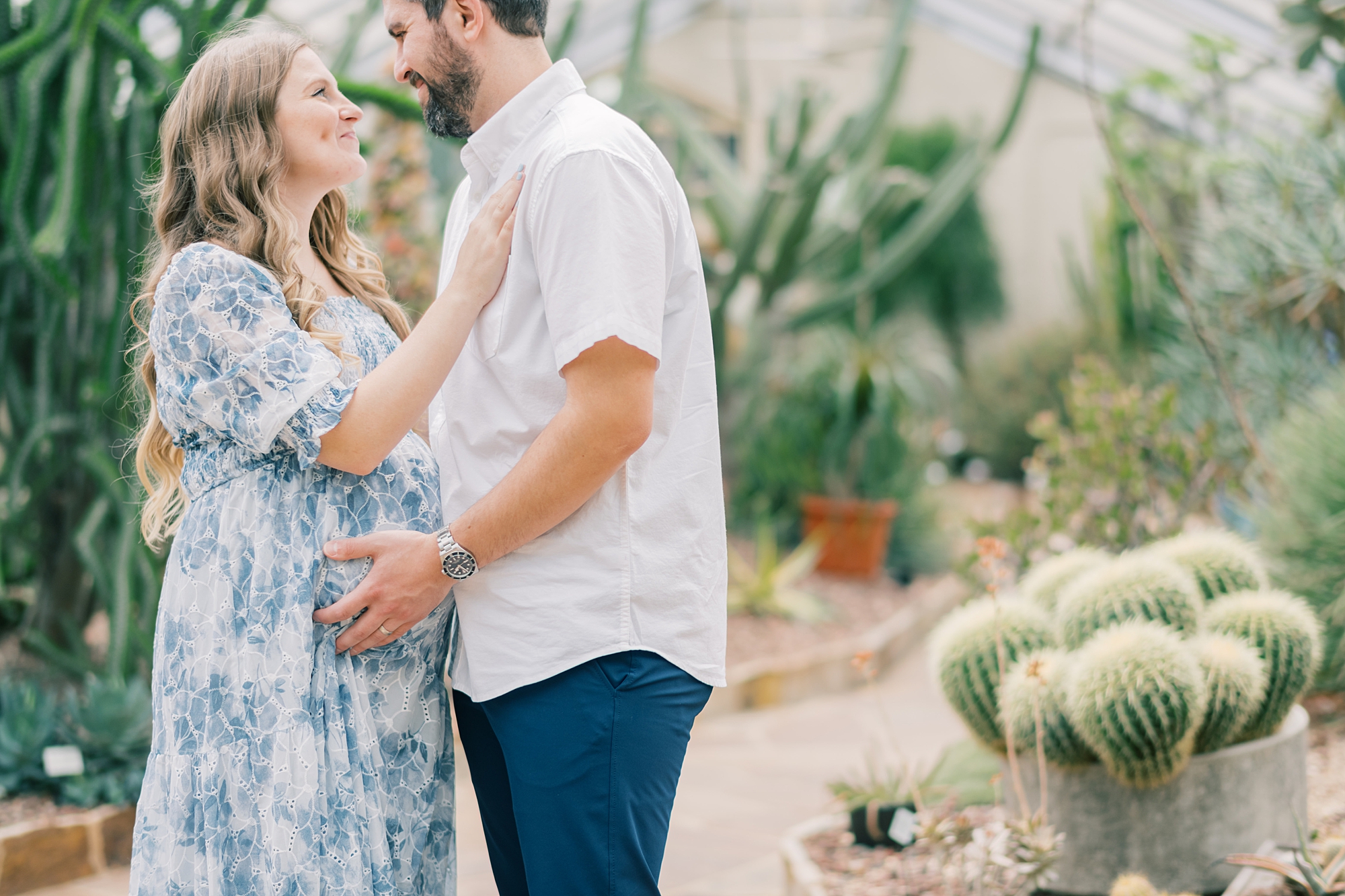 couple hugs inside Rawlings Conservatory during maternity portraits 