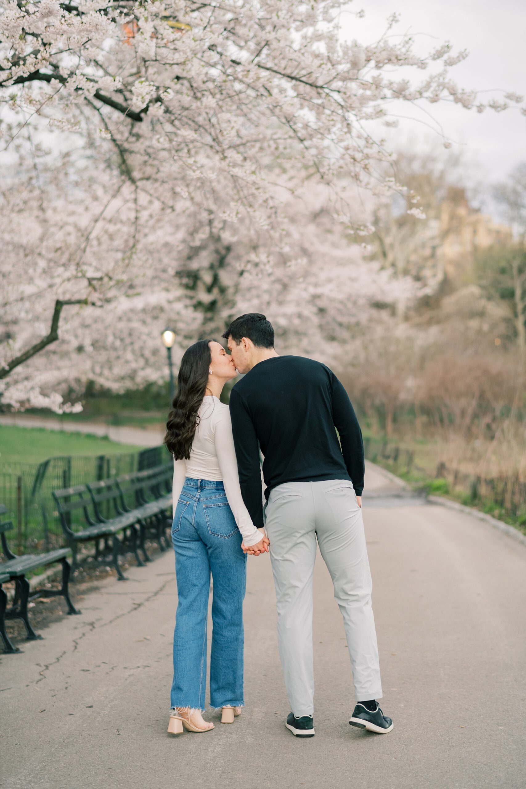 man holds woman's hand leaning to kiss her during engagement session in New York City