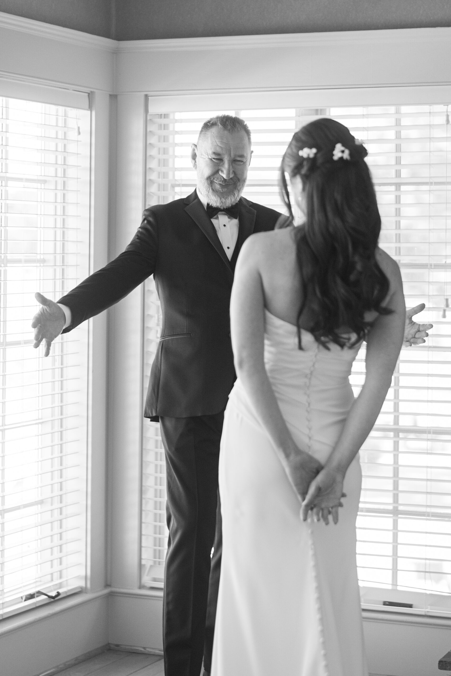 dad reaches to give bride a hug during first look in suite at Herrington on the Bay