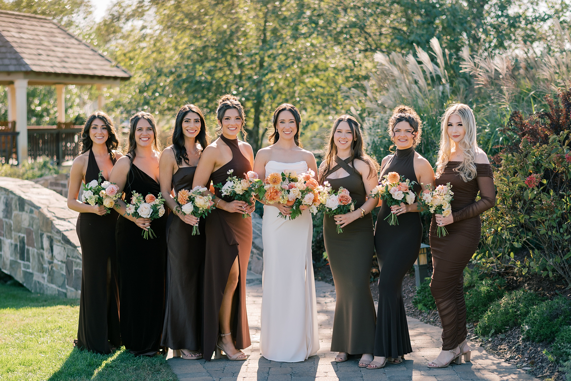 bride poses with bridesmaids in dark gowns for fall wedding