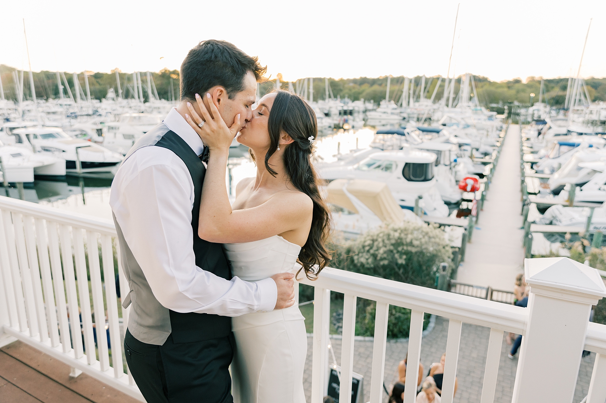 bride and groom kiss on balcony overlooking marina at Herrington on the Bay