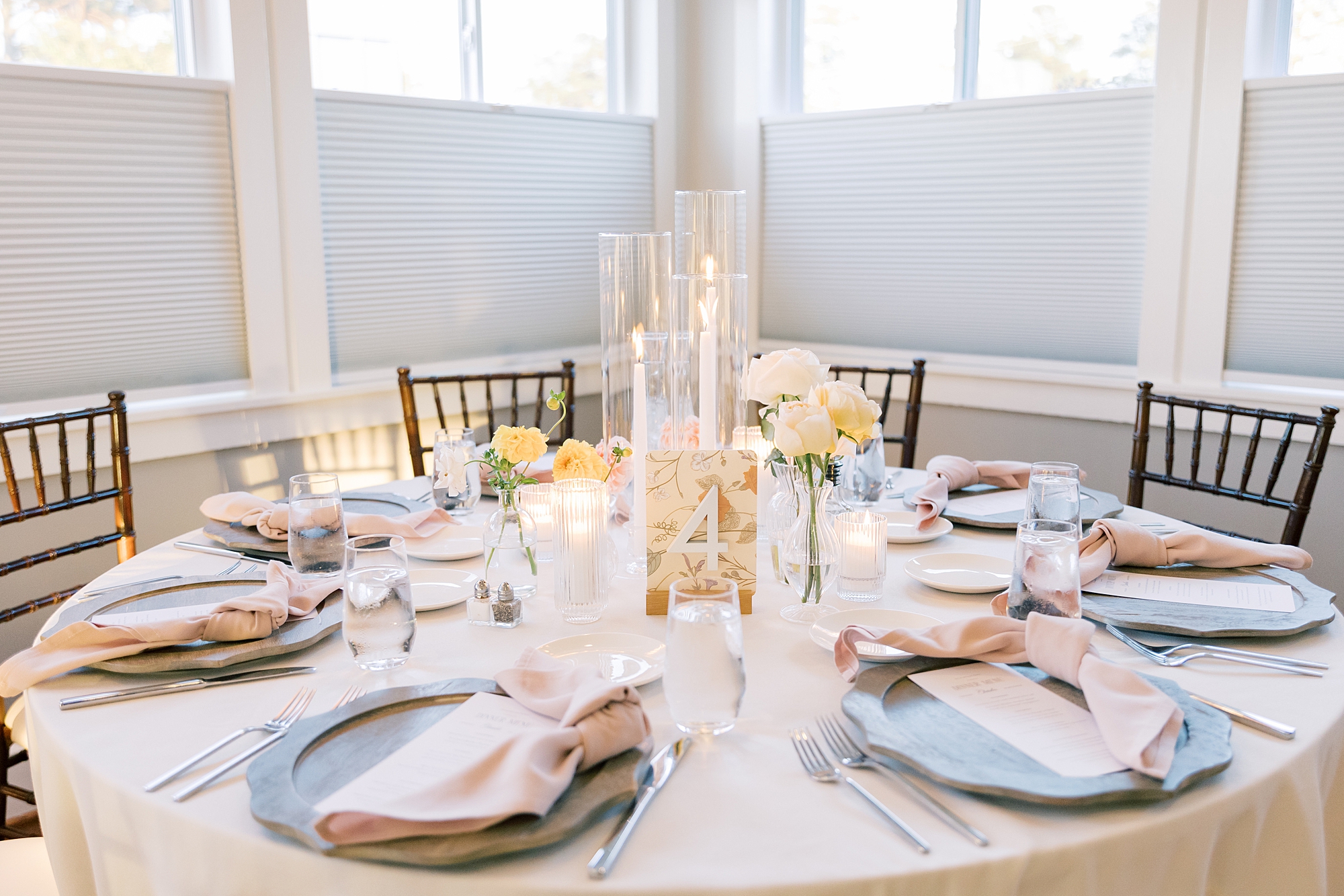 wedding reception with peach and white flowers and thin candles 