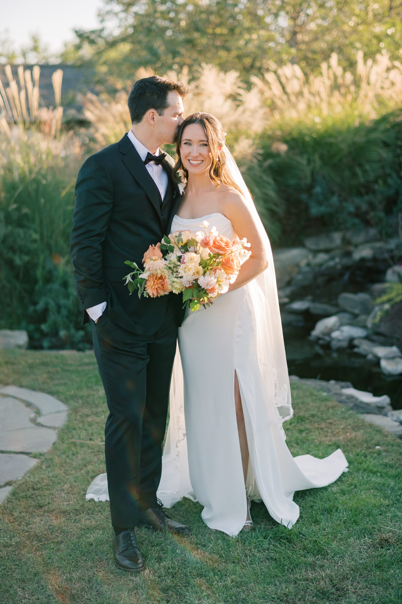 groom kisses bride's head hugging her close to him