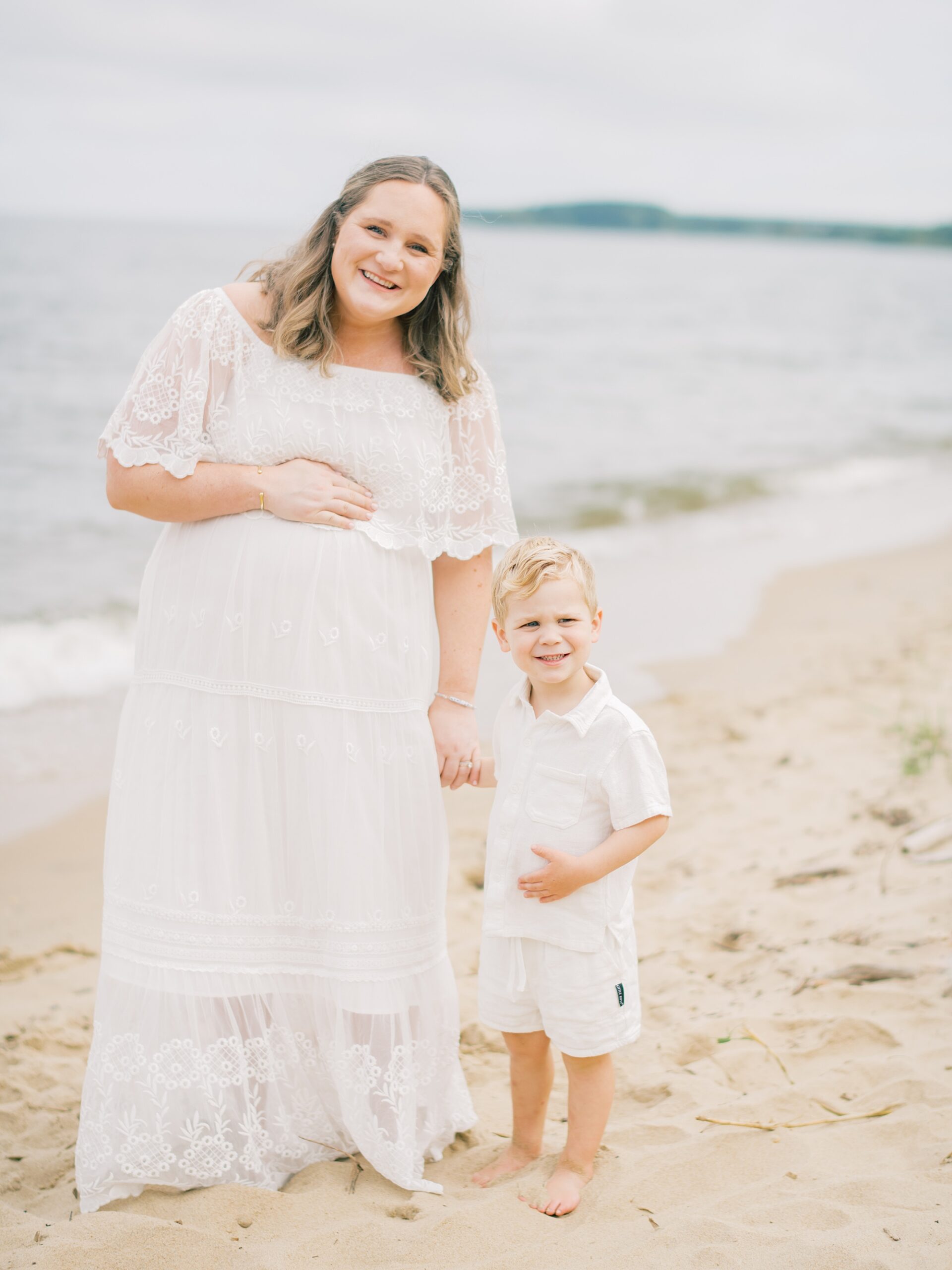 mom stands with son on Terrapin Park beach during maternity session in Annapolis Maryland