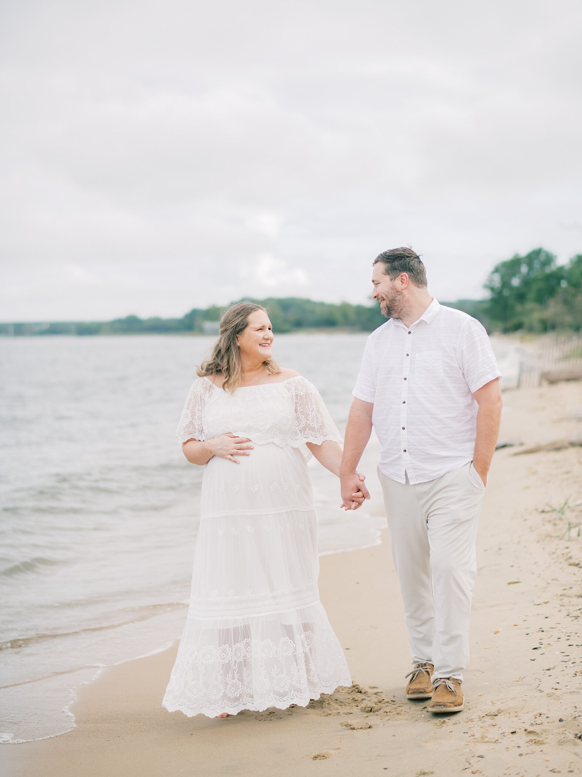 couple holds hands walking on the beach at Terrapin Park