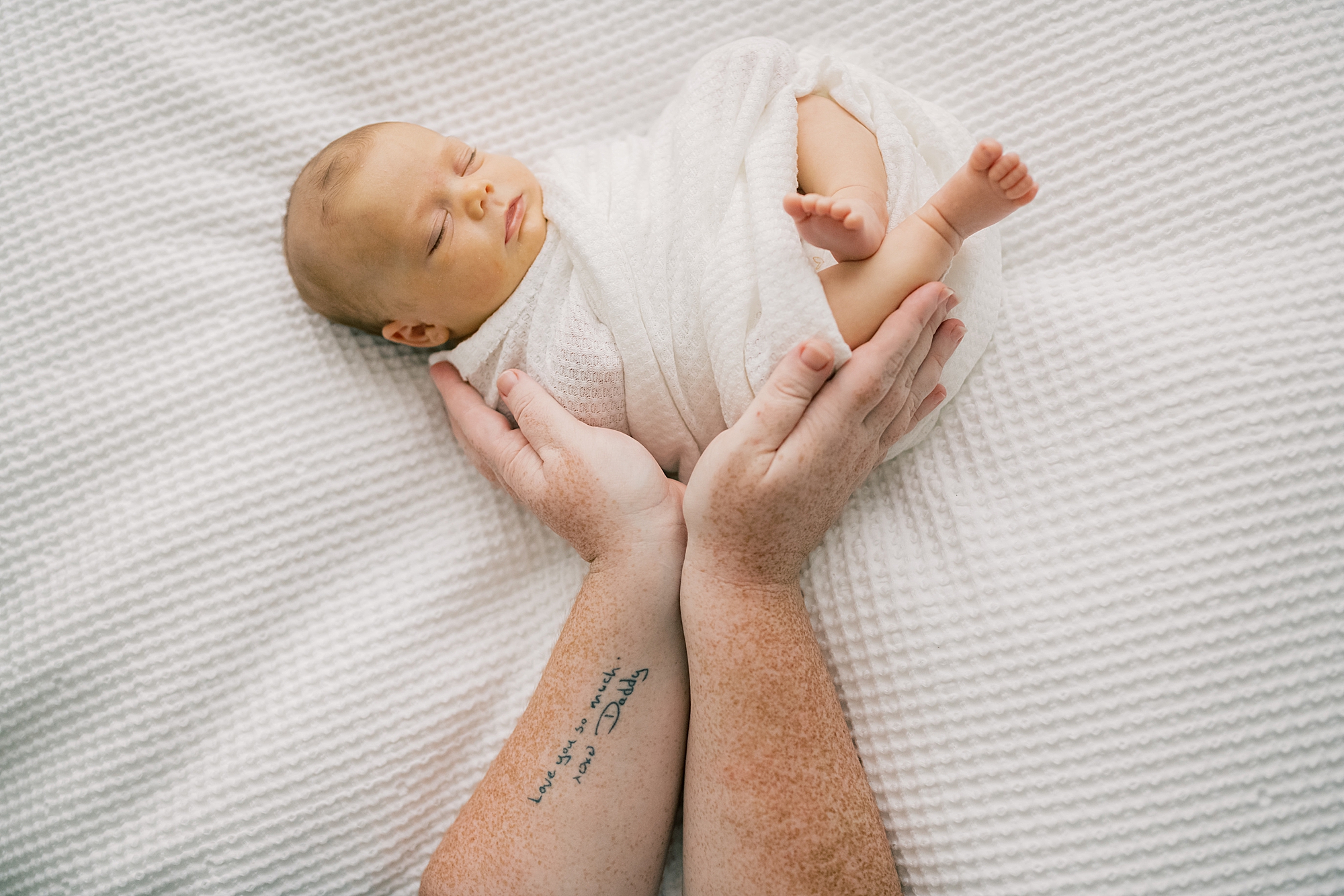 mother holds baby showing off tattoo in late father's writing 