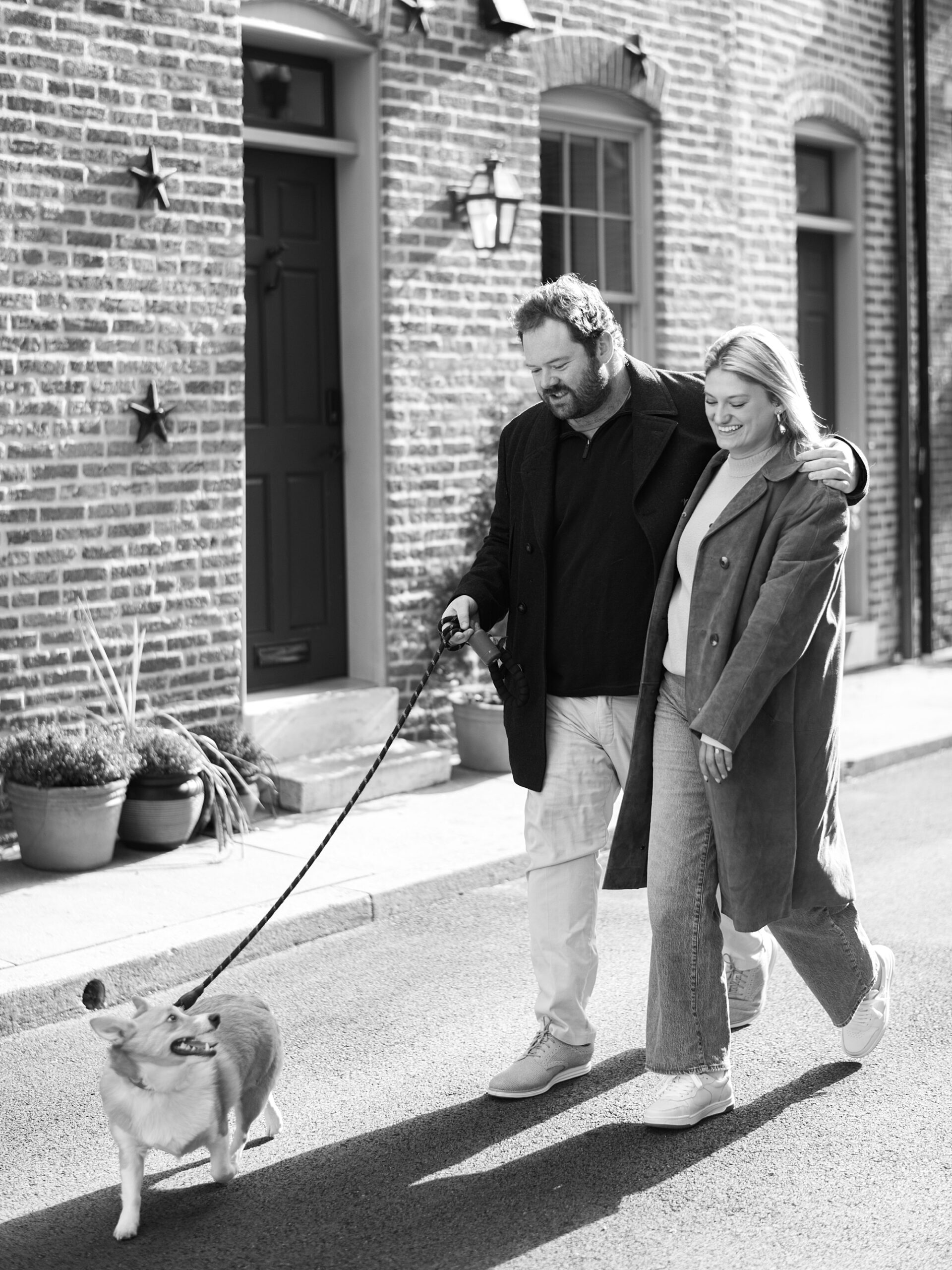 couple walks dog in front of brick buildings in Fells Point 