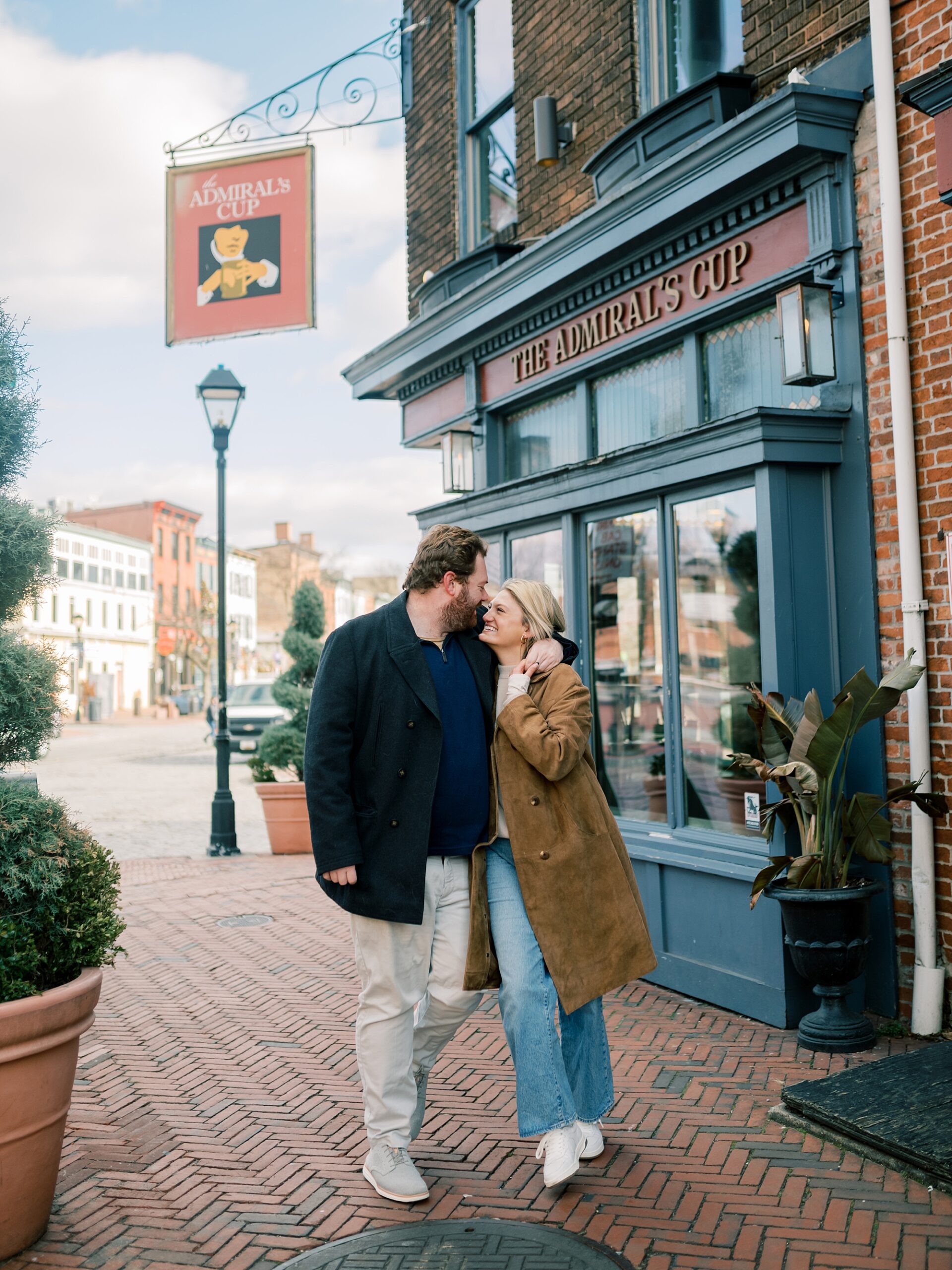 engaged couple hugs by bar in downtown Baltimore neighborhood 