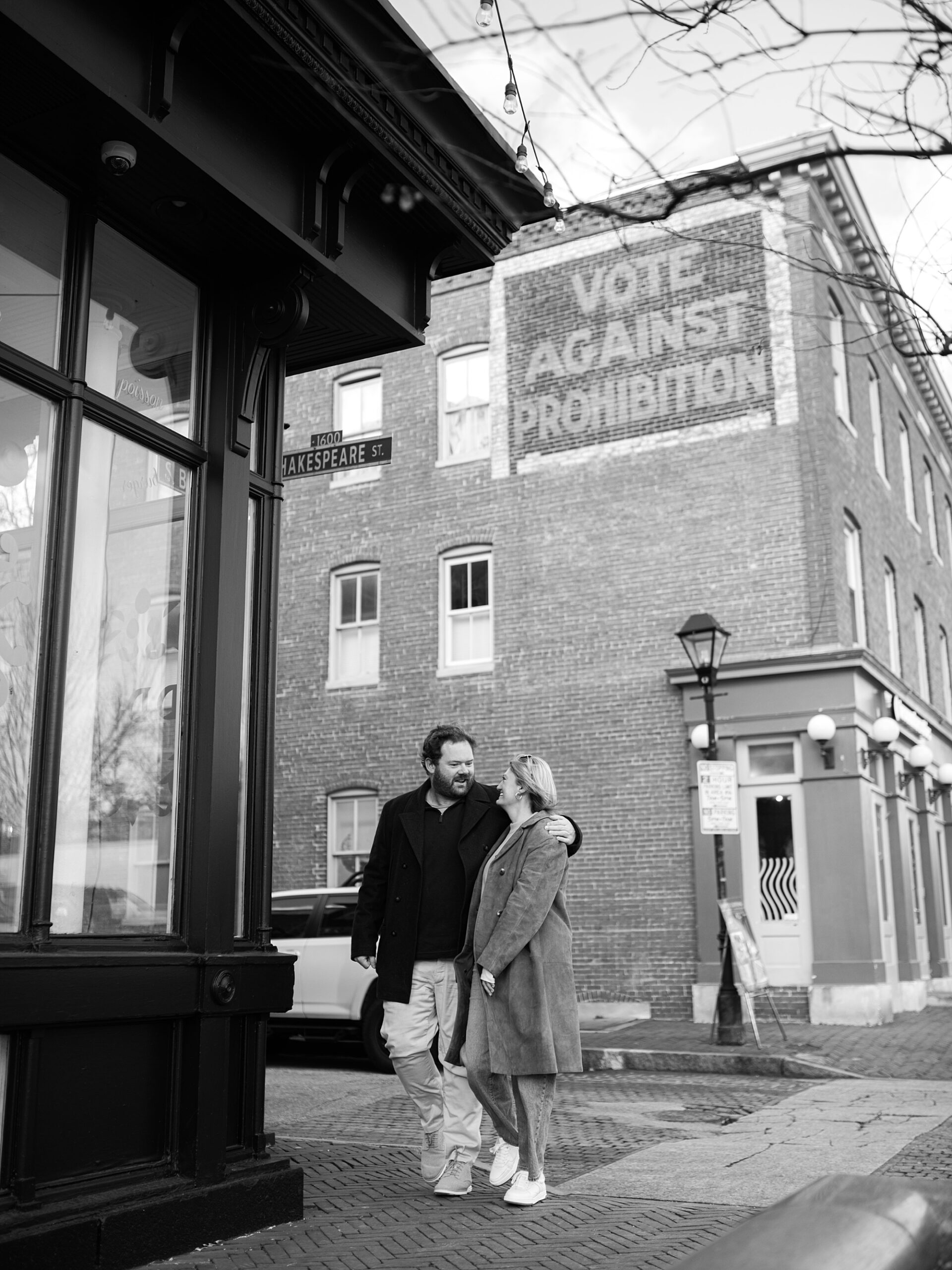 couple hugs in front of brick building in Baltimore neighborhood 