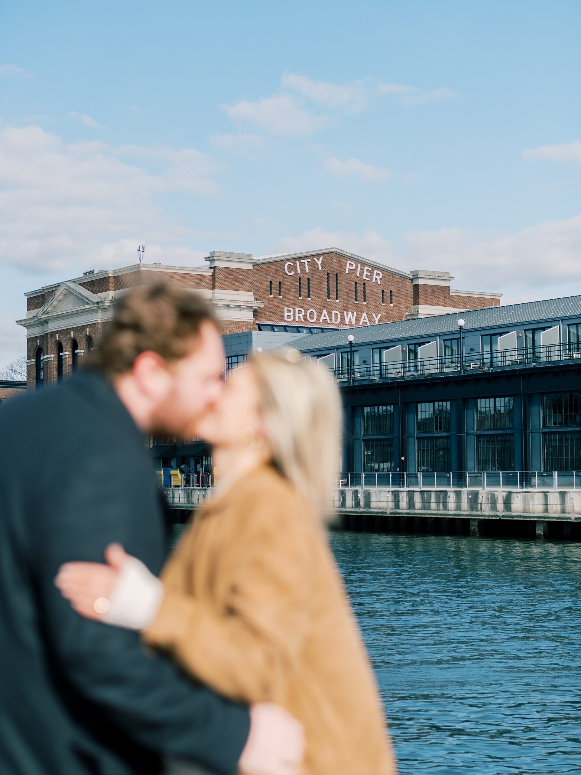 man and woman kiss in front of bridge in Baltimore MD