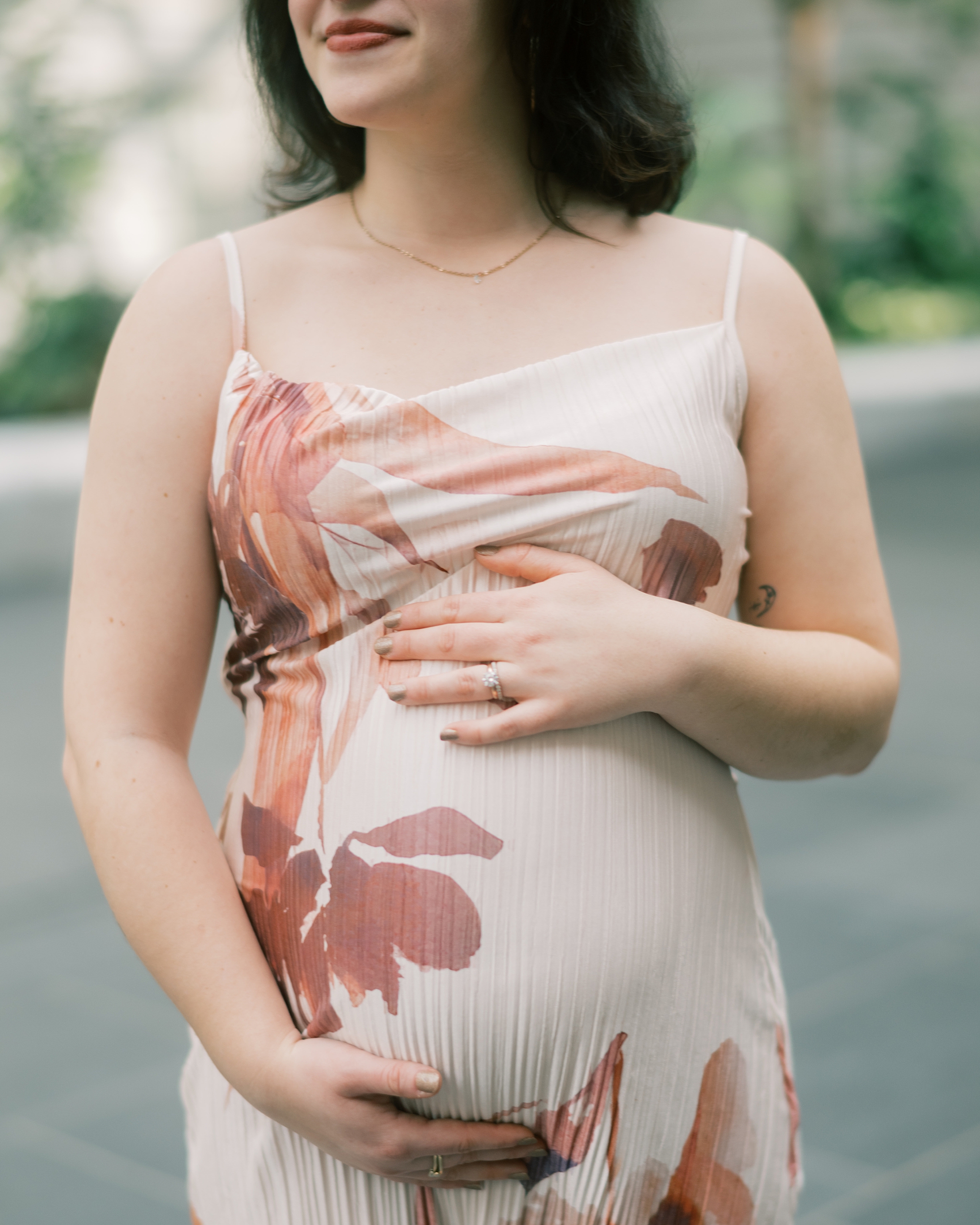 pregnant woman holds baby bump in spring flower dress