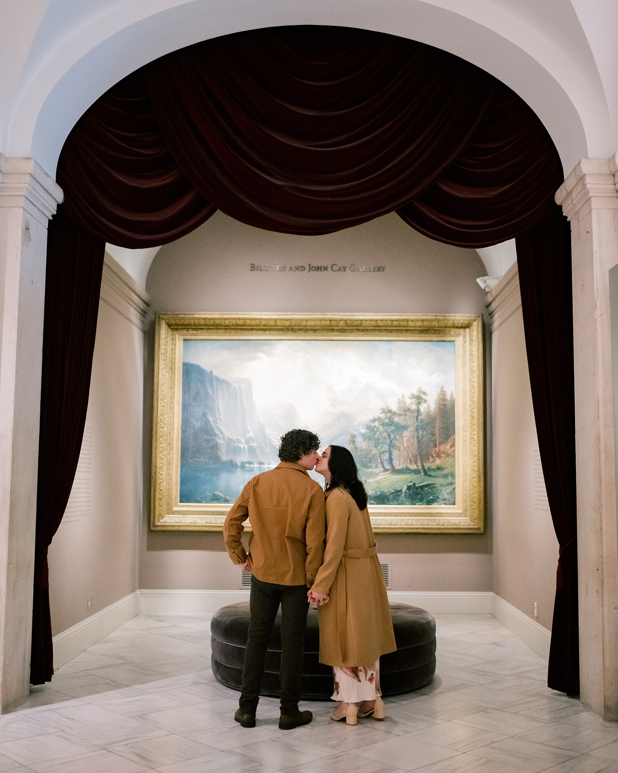 man and woman kiss in front of painting inside the National Portrait Gallery