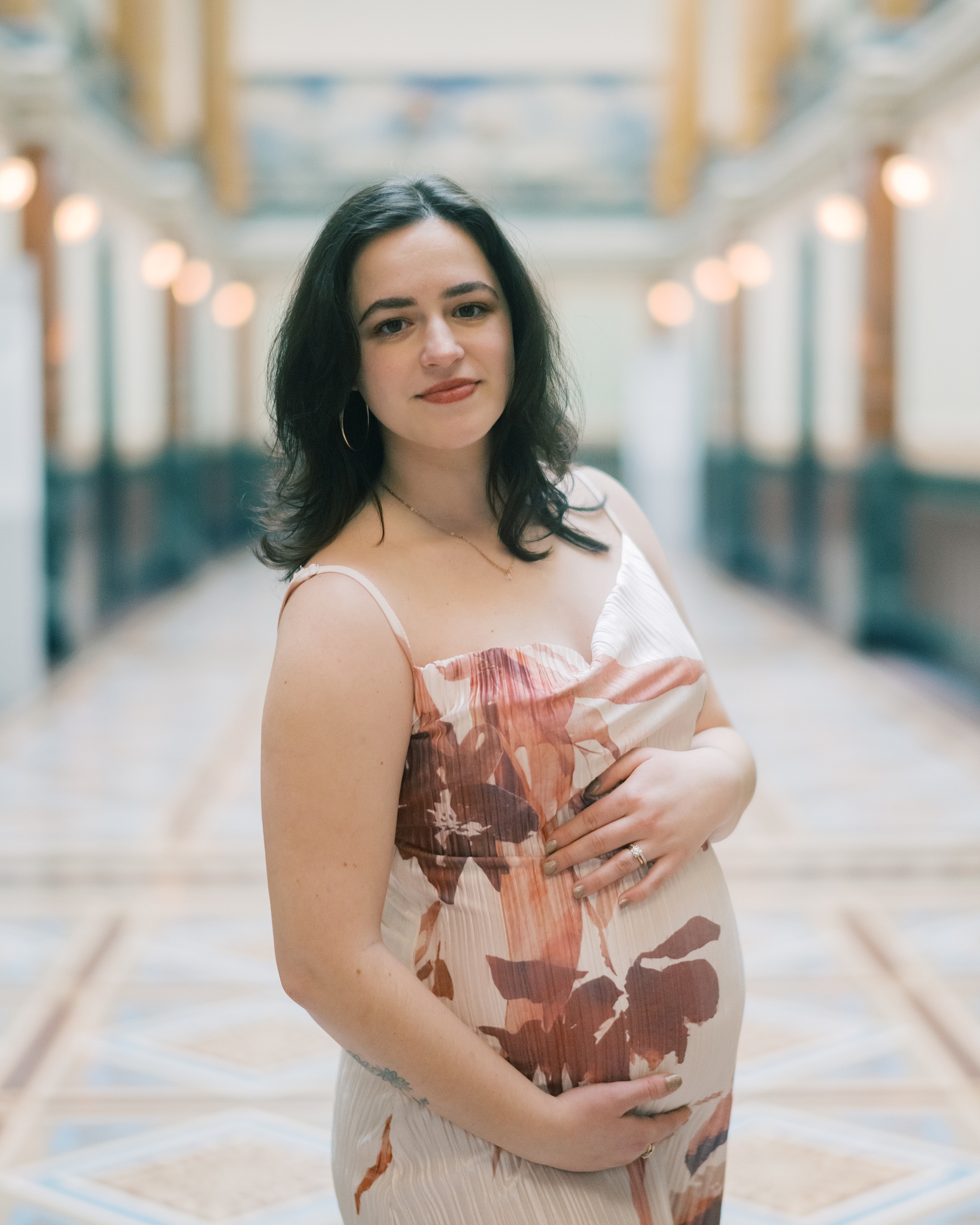 expecting mother holds baby bump in spring dress during maternity session in DC