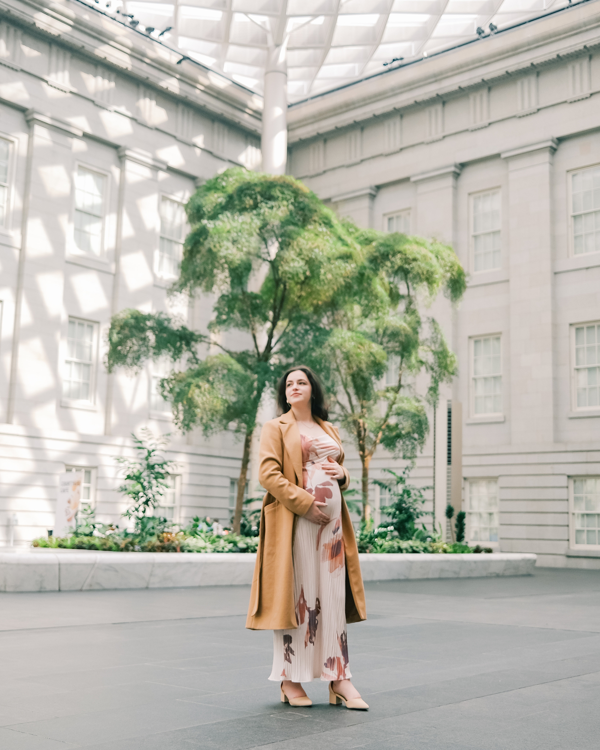 woman stands holding baby bump in corner of National Portrait Gallery