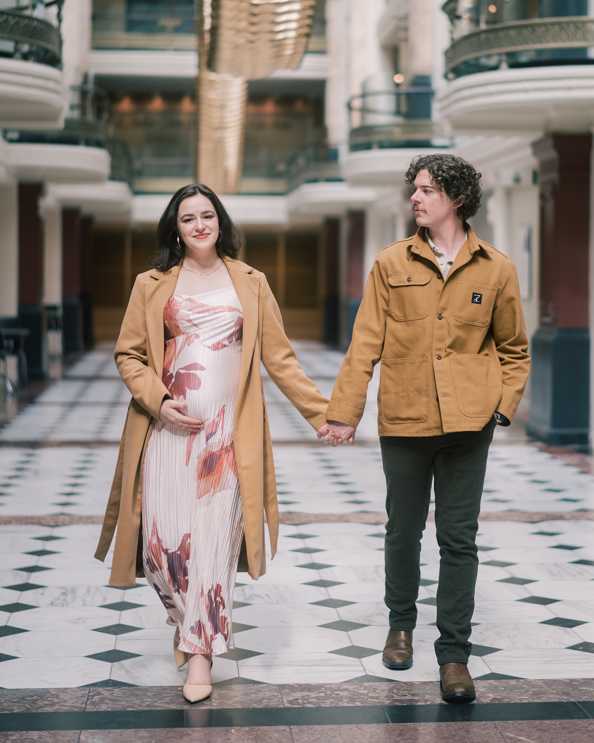 expecting parents hold hands walking through the National Portrait Gallery