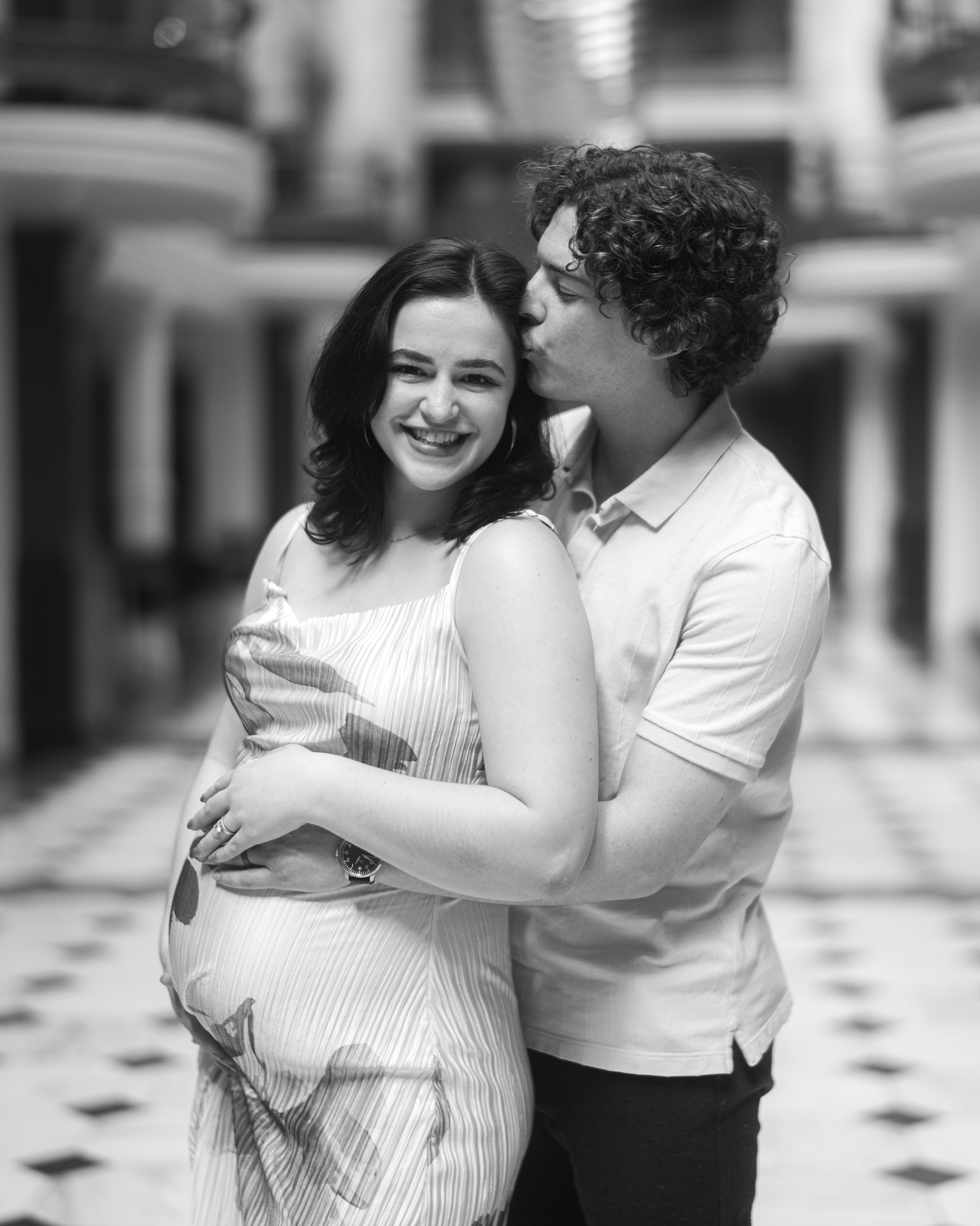 man hugs woman from behind during maternity session at the National Portrait Gallery