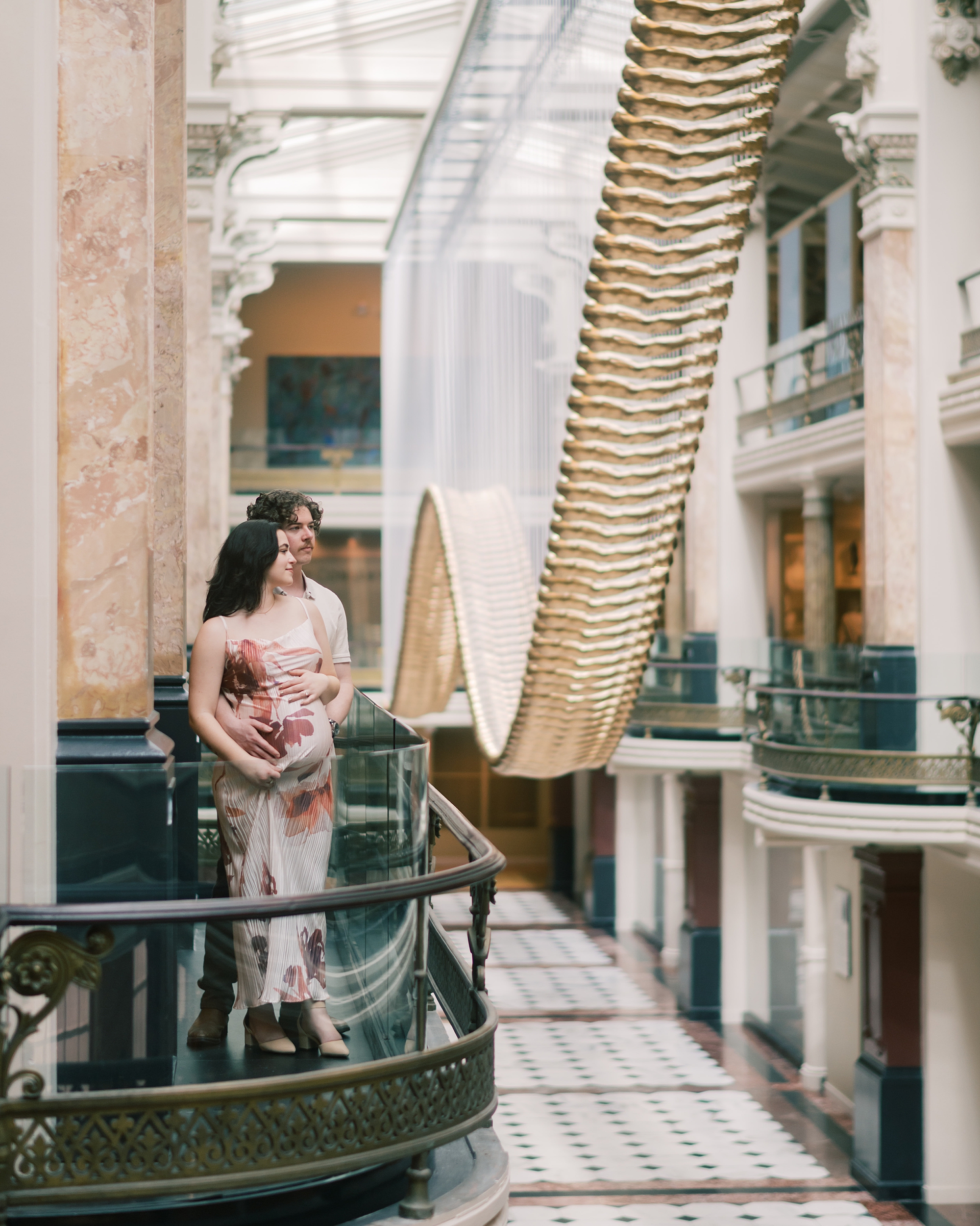couple stands on balcony overlooking installation at the National Portrait Gallery