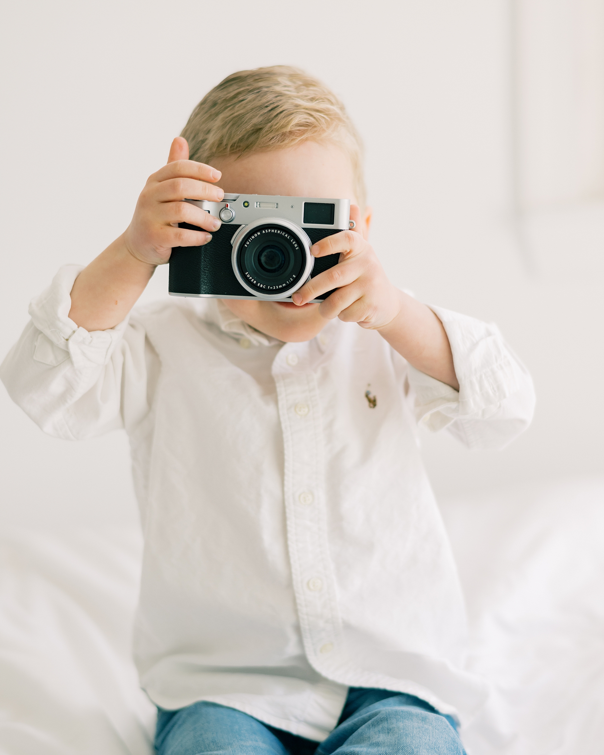 toddler holds up point and click Fuji camera in Costola Studio