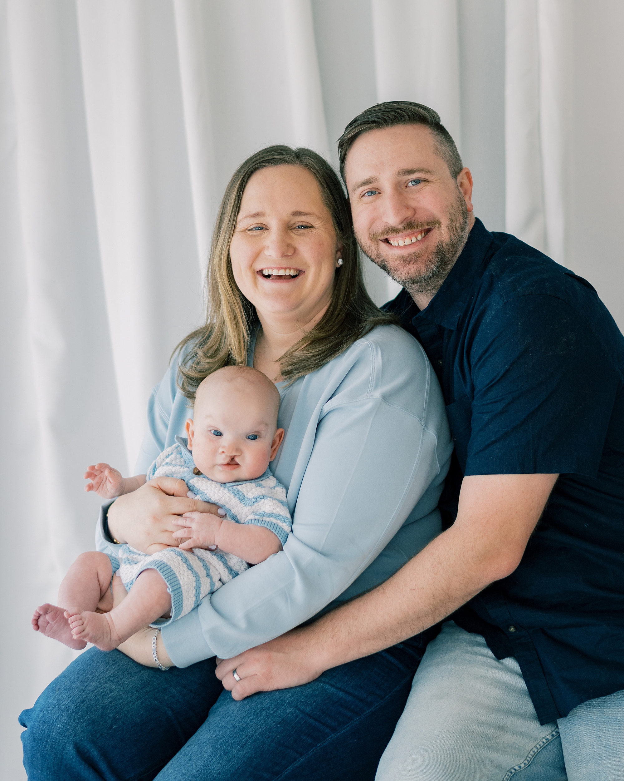 dad hugs mom while she holds baby boy with cleft palate in Costola Studio